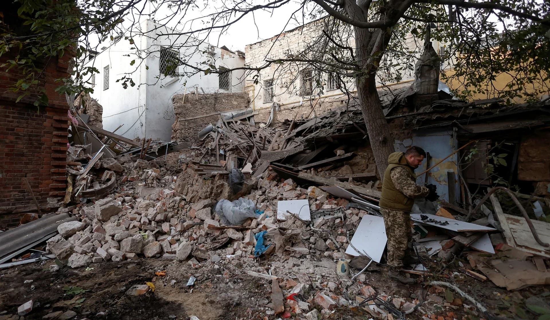 A Ukrainian serviceman collects remains of a missile at the site of a residential building heavily damaged during a Russian attack in Mykolaiv
