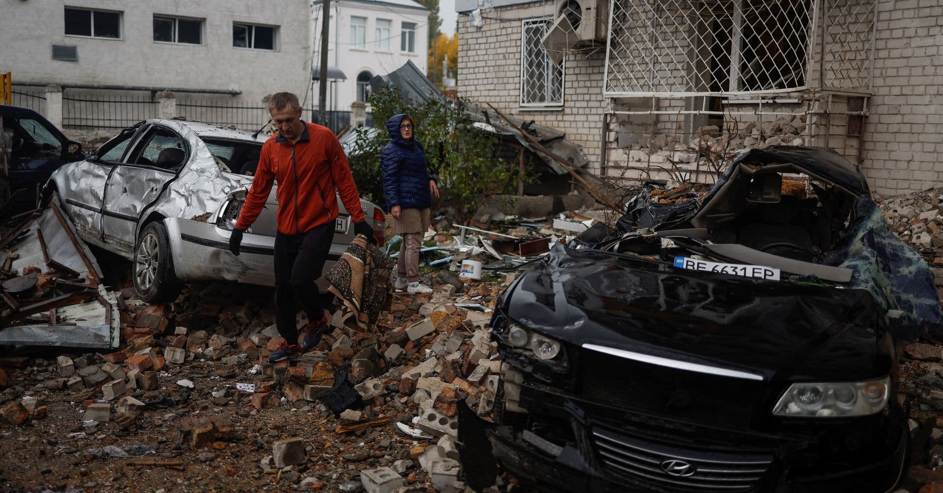 A local resident walks past cars damaged by a Russian missile attack in Mykolaiv