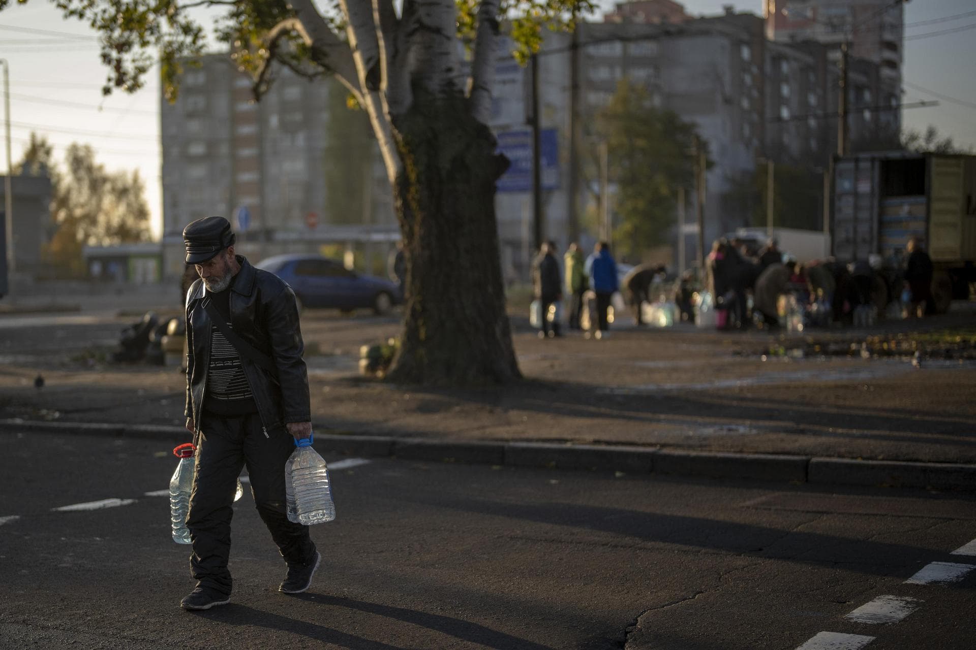 A man carries plastic bottles after refilling them in a tank, in the center of Mykolaiv