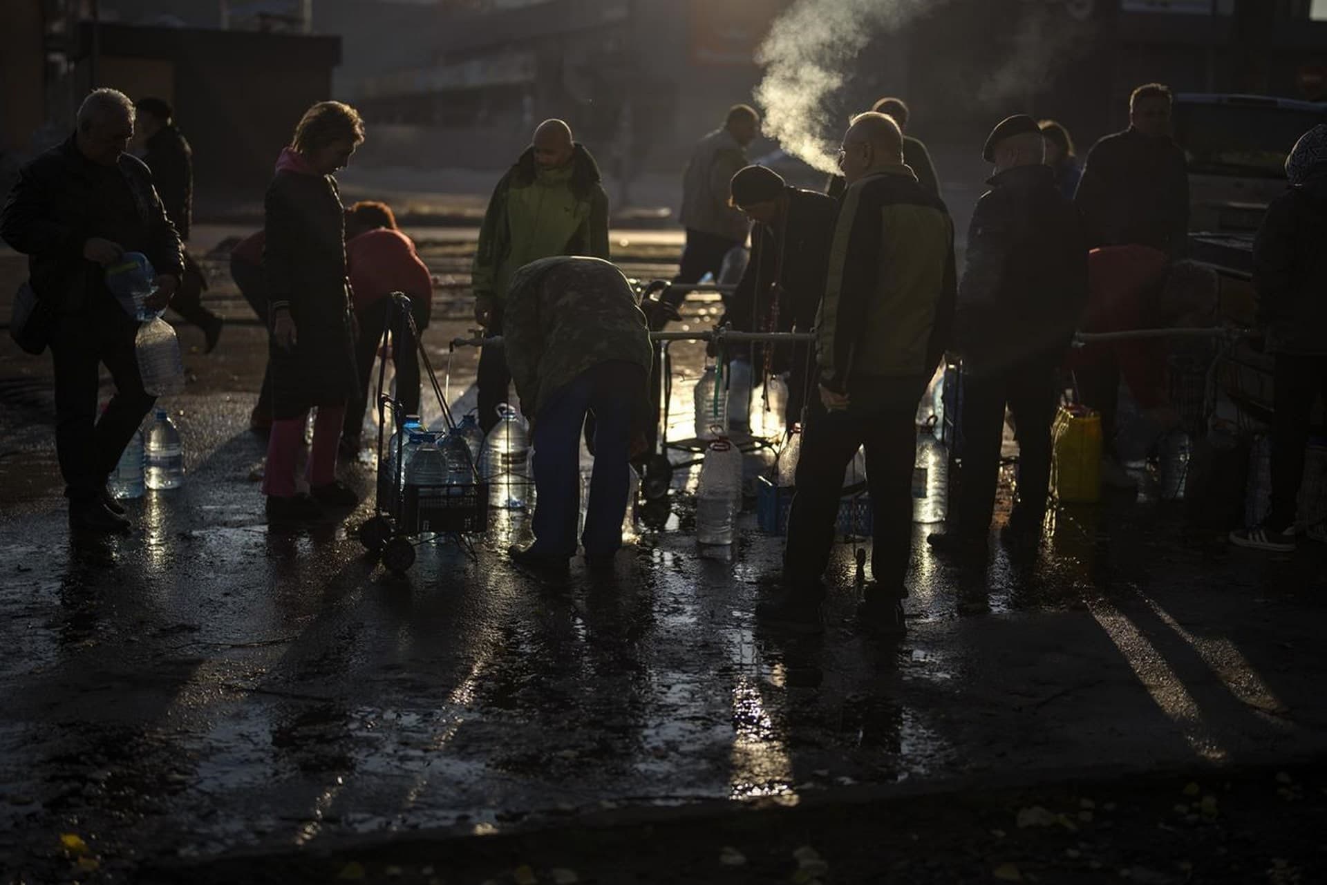 People refill their plastic bottles with drinking water from a tank in the center of Mykolaiv