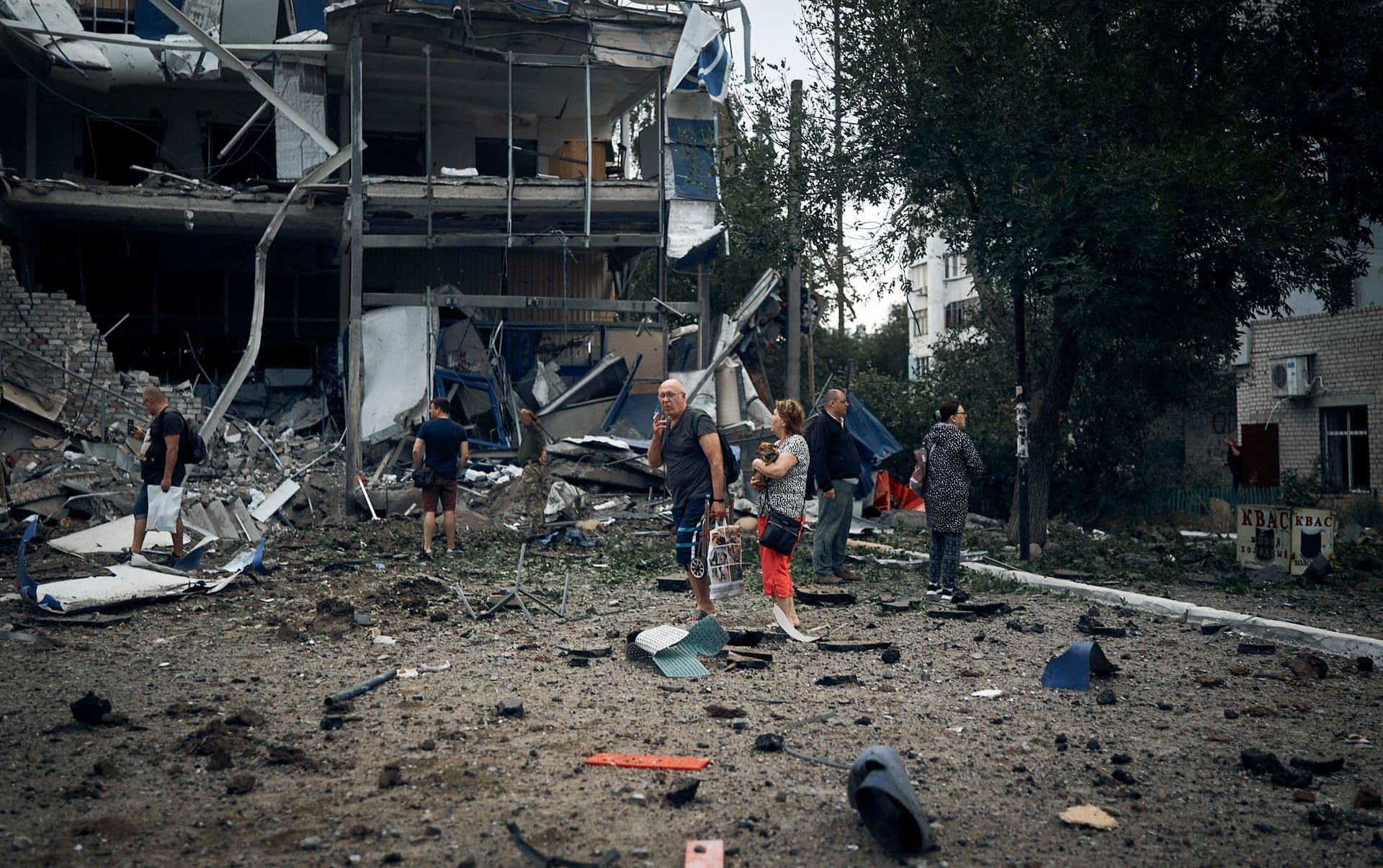 People stand in front of destroyed buildings after the Russian shelling in Mykolaiv