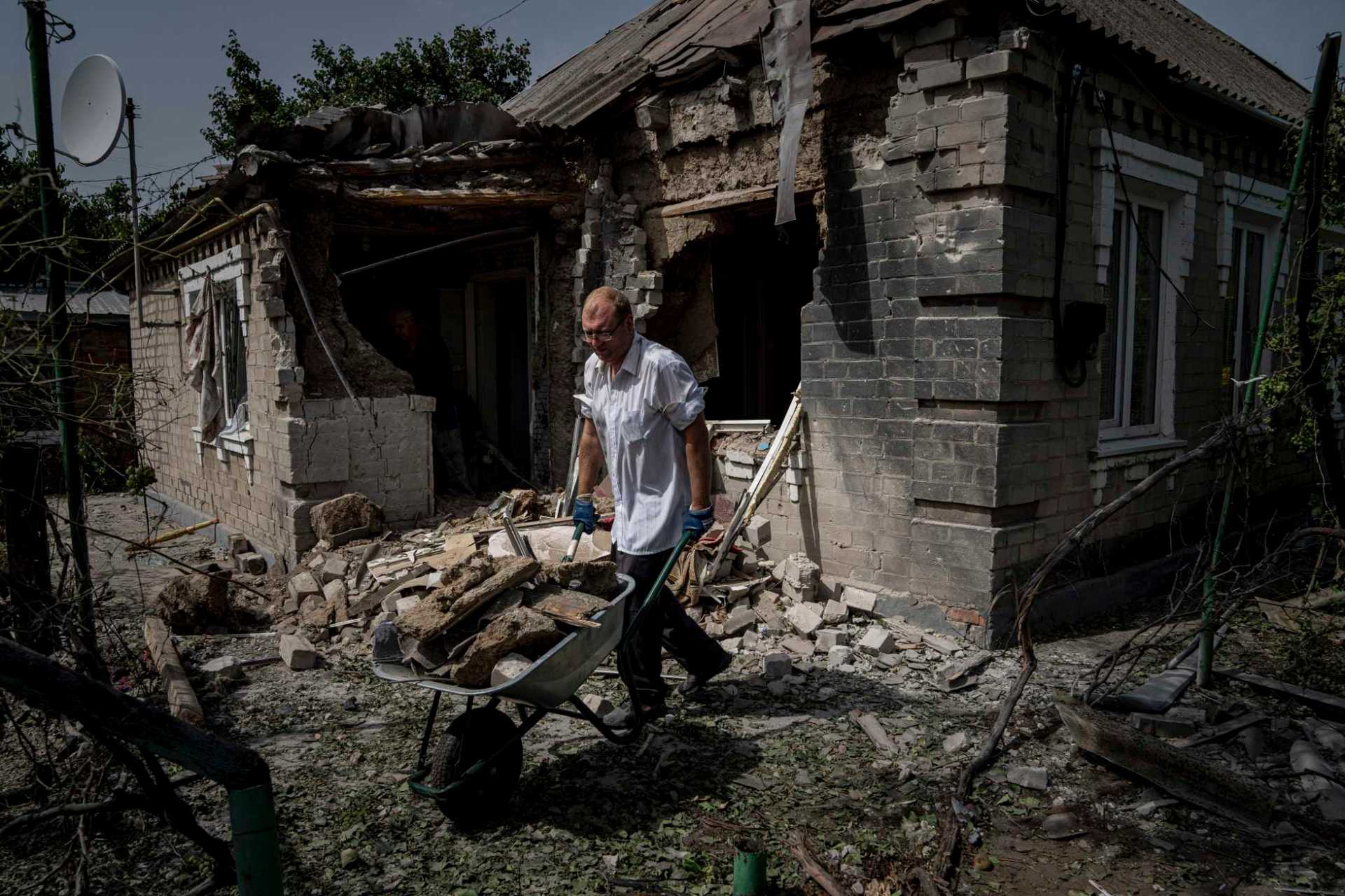 Dmyto Shengur cleans rubble in front of the house which was damaged after Russian bombardment of residential area in Nikopol