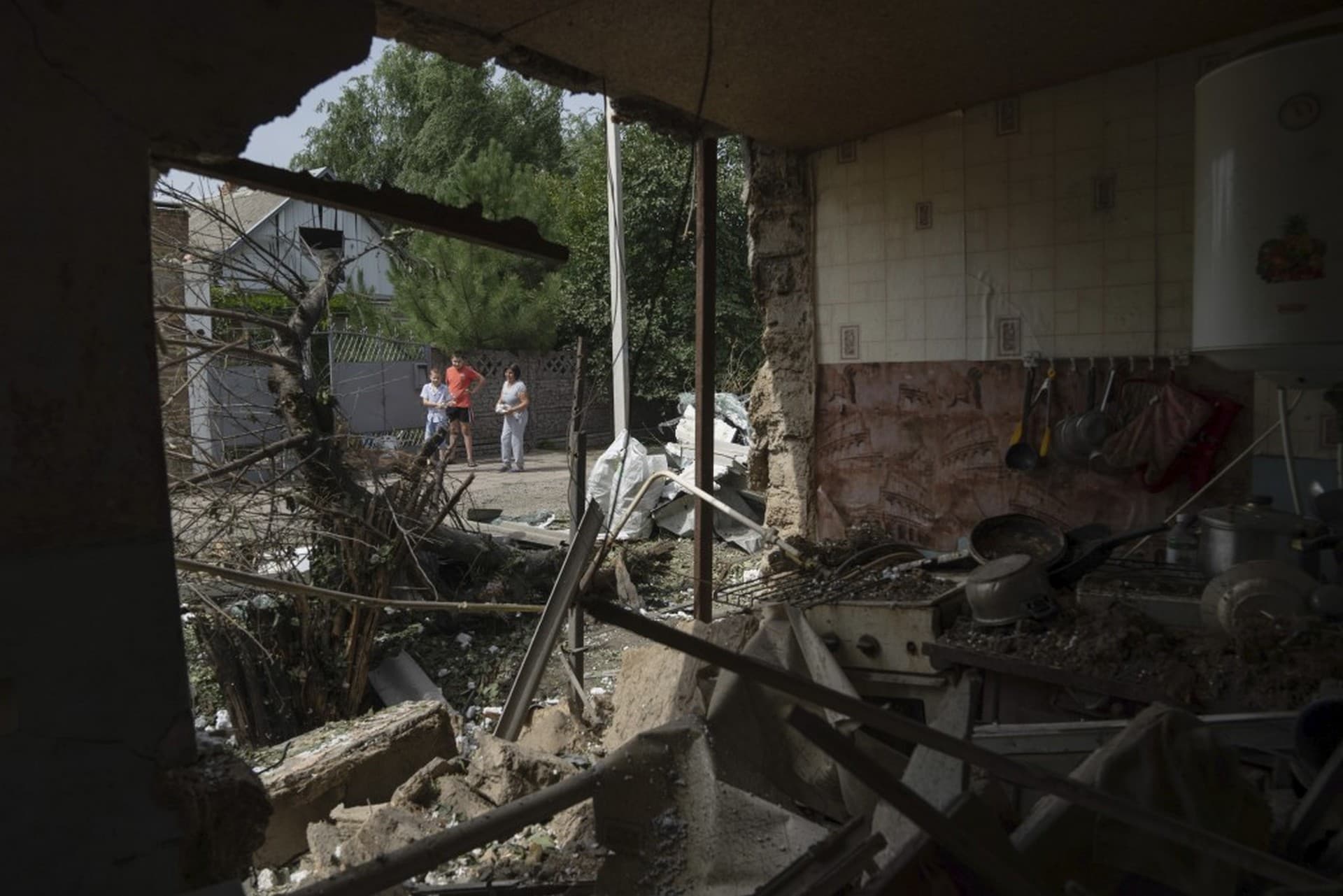People look on a house which was damaged after Russian bombardment of residential area in Nikopol