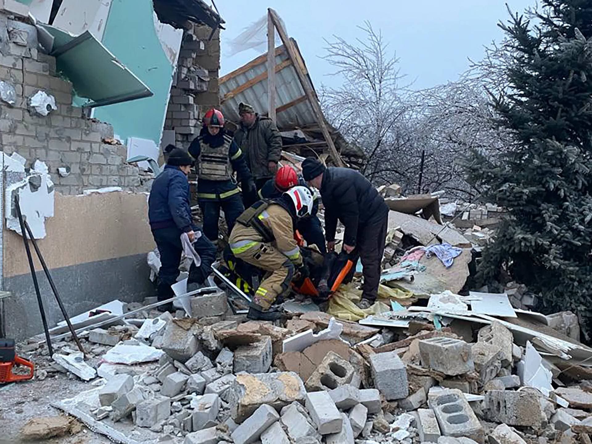 Rescuers help a wounded person after homes were destroyed by a Russian missile attack in Novomoskovsk