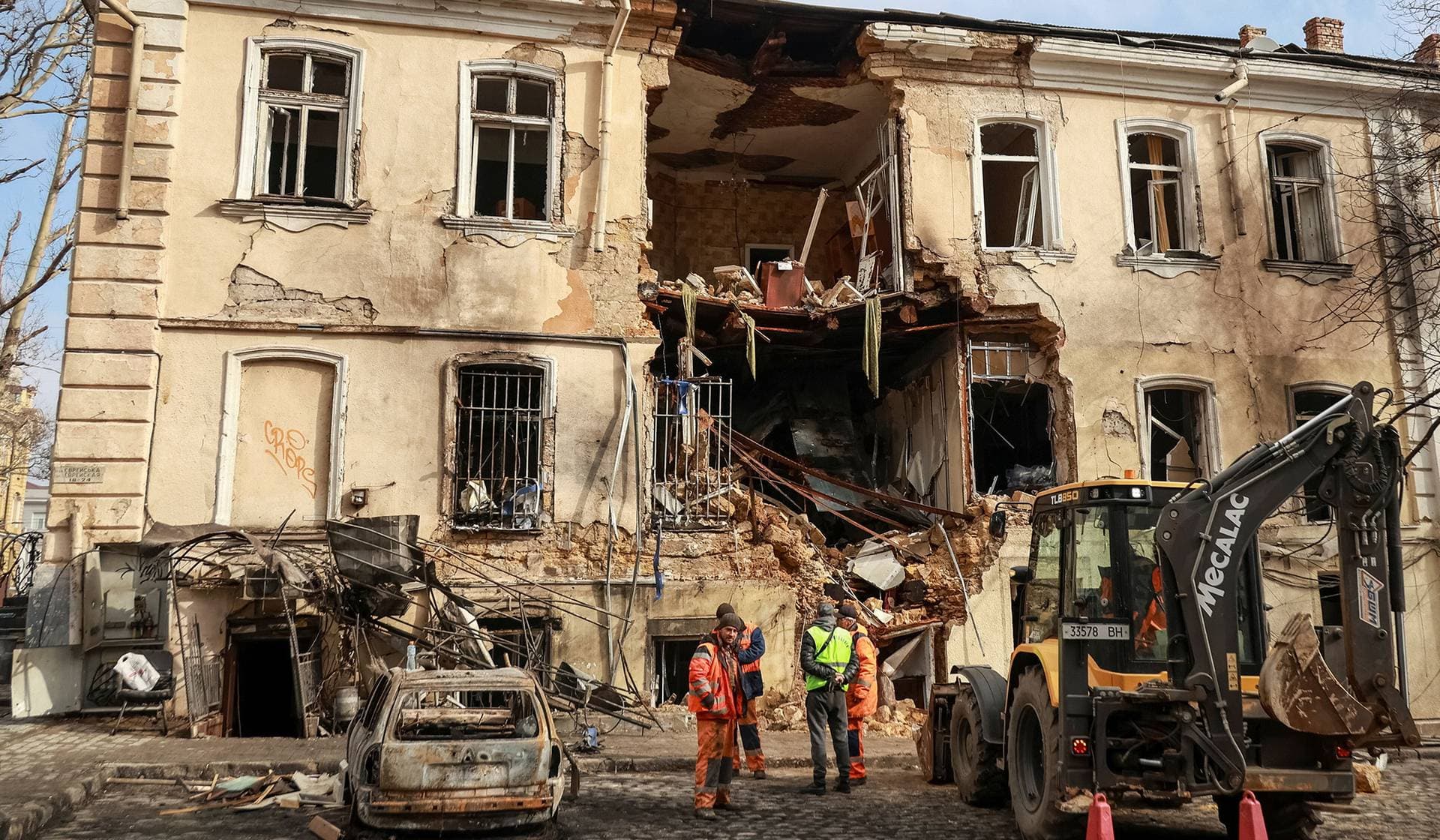 Communal workers clean an area at the site of an apartment building hit by a Russian drone strike in Odesa