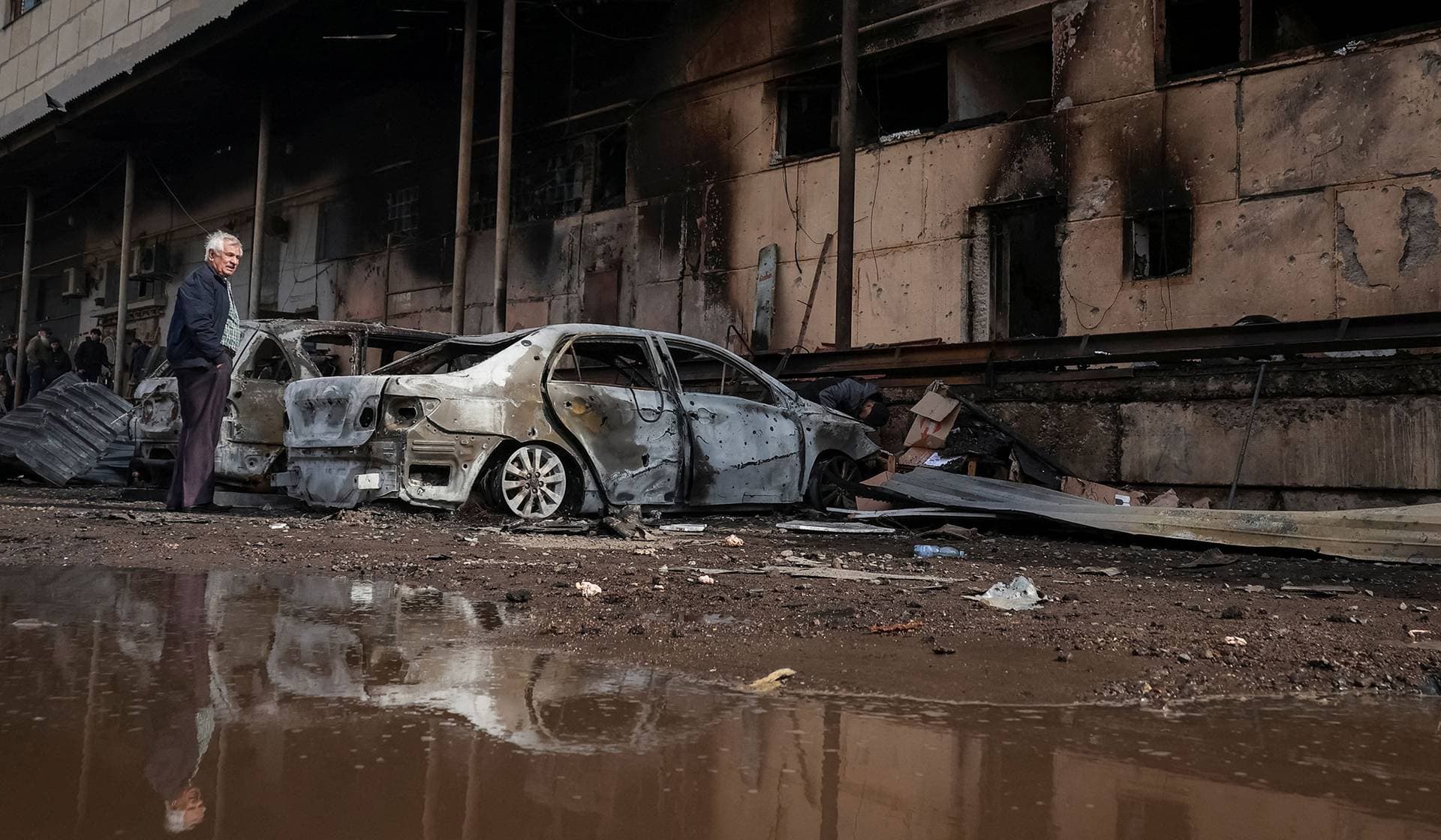 A resident stands next to his destroyed car at the site of a Russian drone strike in Odesa