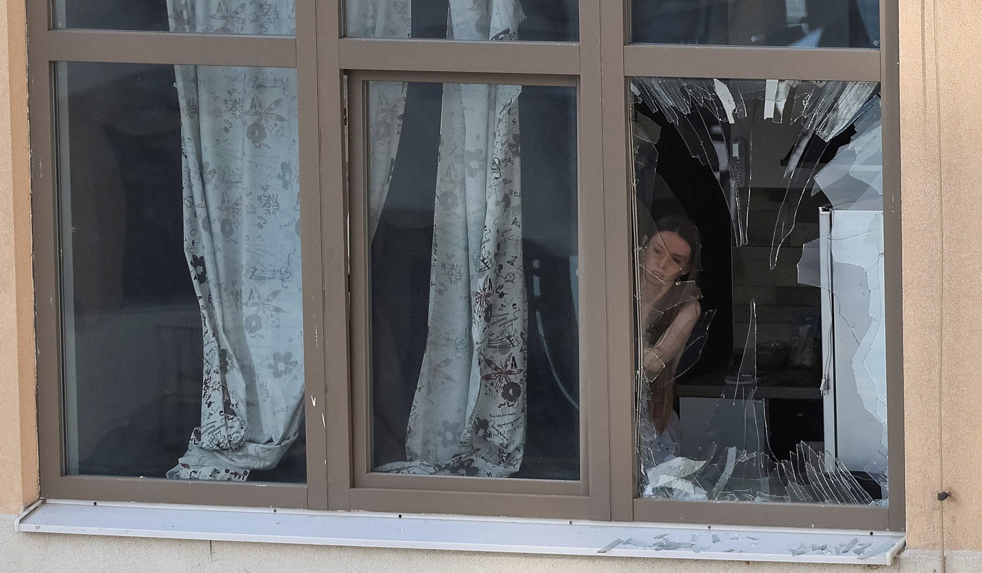 A woman removes a broken window from an apartment building damaged during a Russian drone strike in Odesa