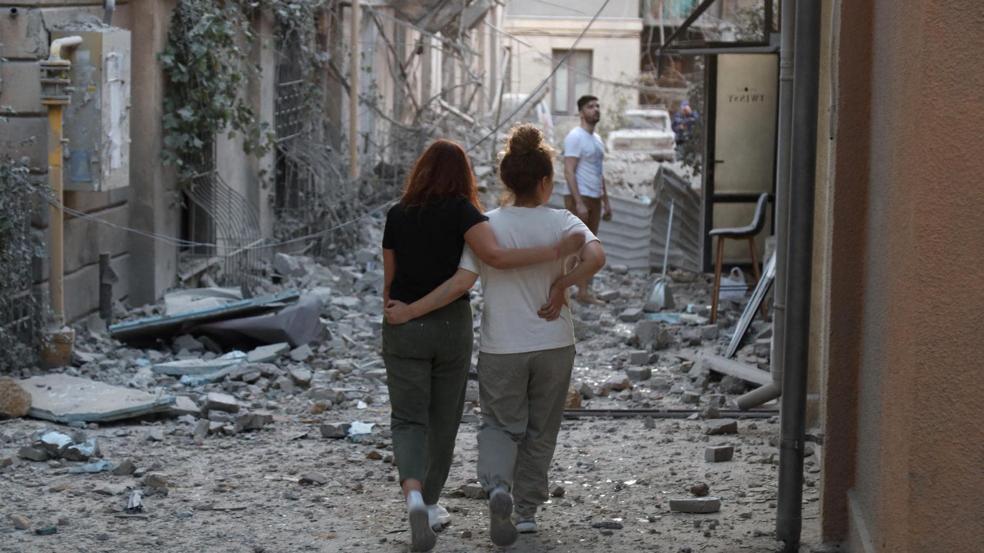 Local residents walk among the rubble of buildings damaged in a Russian missile strike in Odesa