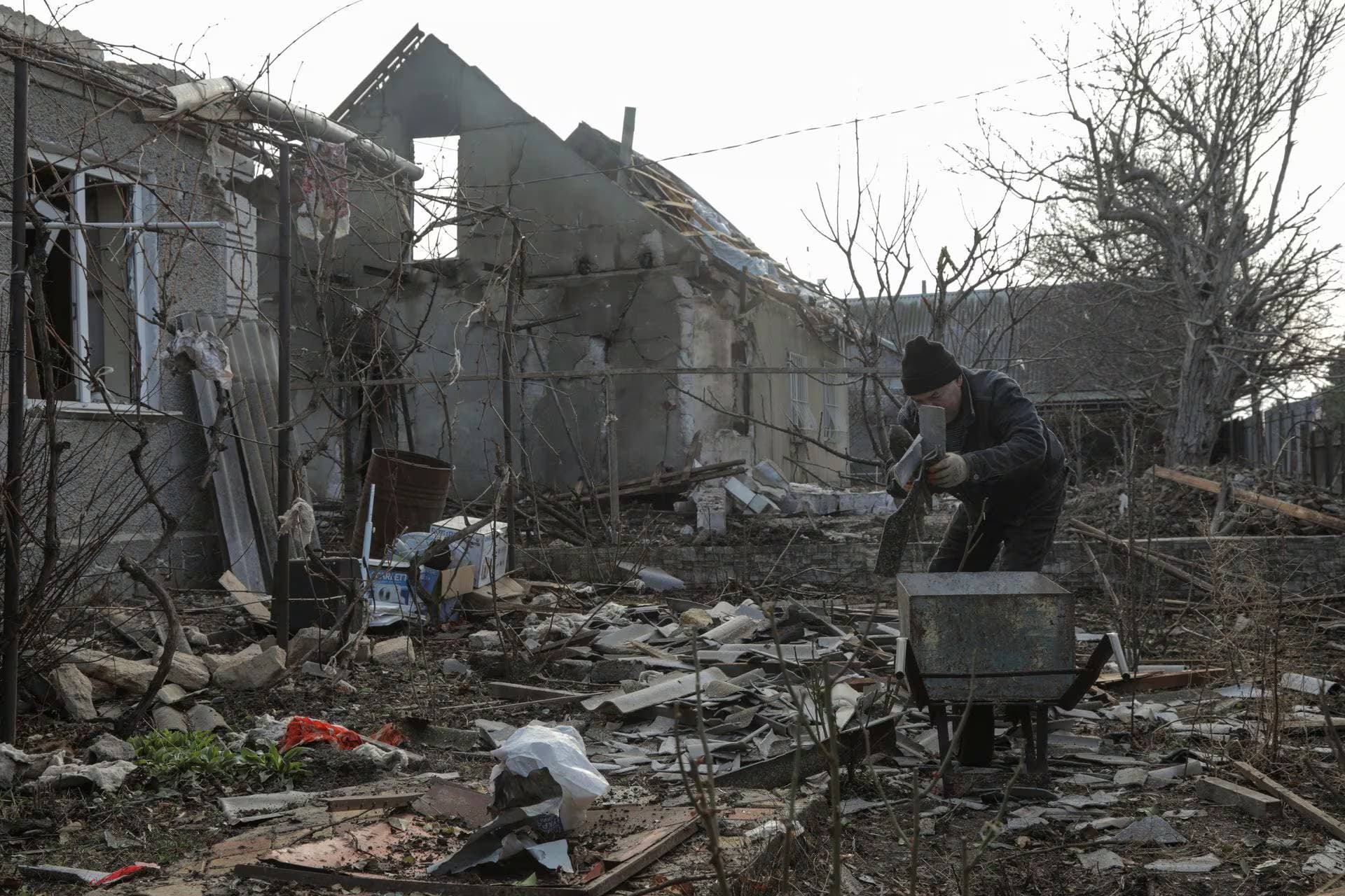 A local resident removes debris from the backyard of his house, which was damaged during a Russian drone strike in Odesa