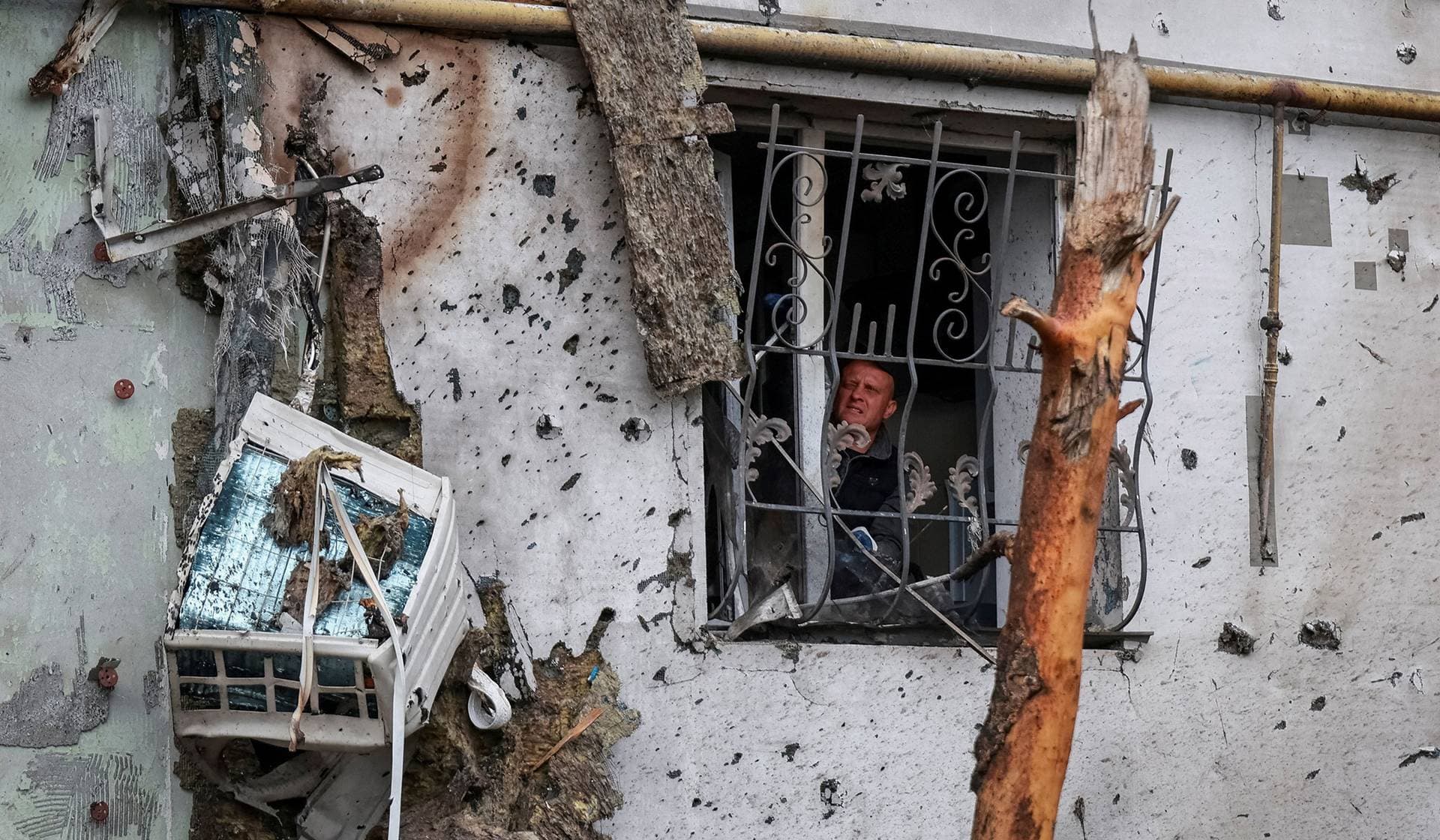 A resident removes broken glass from a window of an apartment building damaged by a Russian drone strike in Odesa