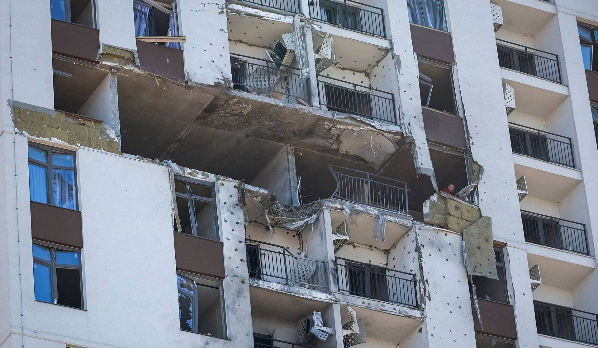 A resident removes debris from his flat in an apartment building damaged by a Russian drone strike in Odesa