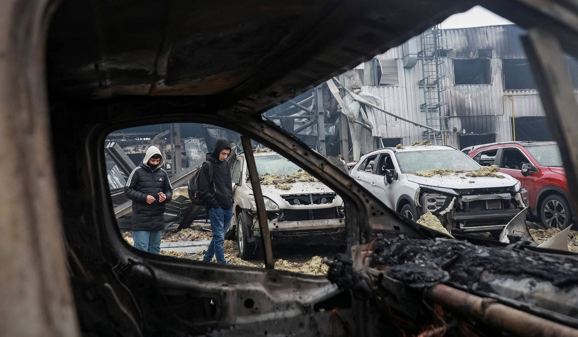 Residents walk near damaged cars at the site of a Russian drone strike in Odesa