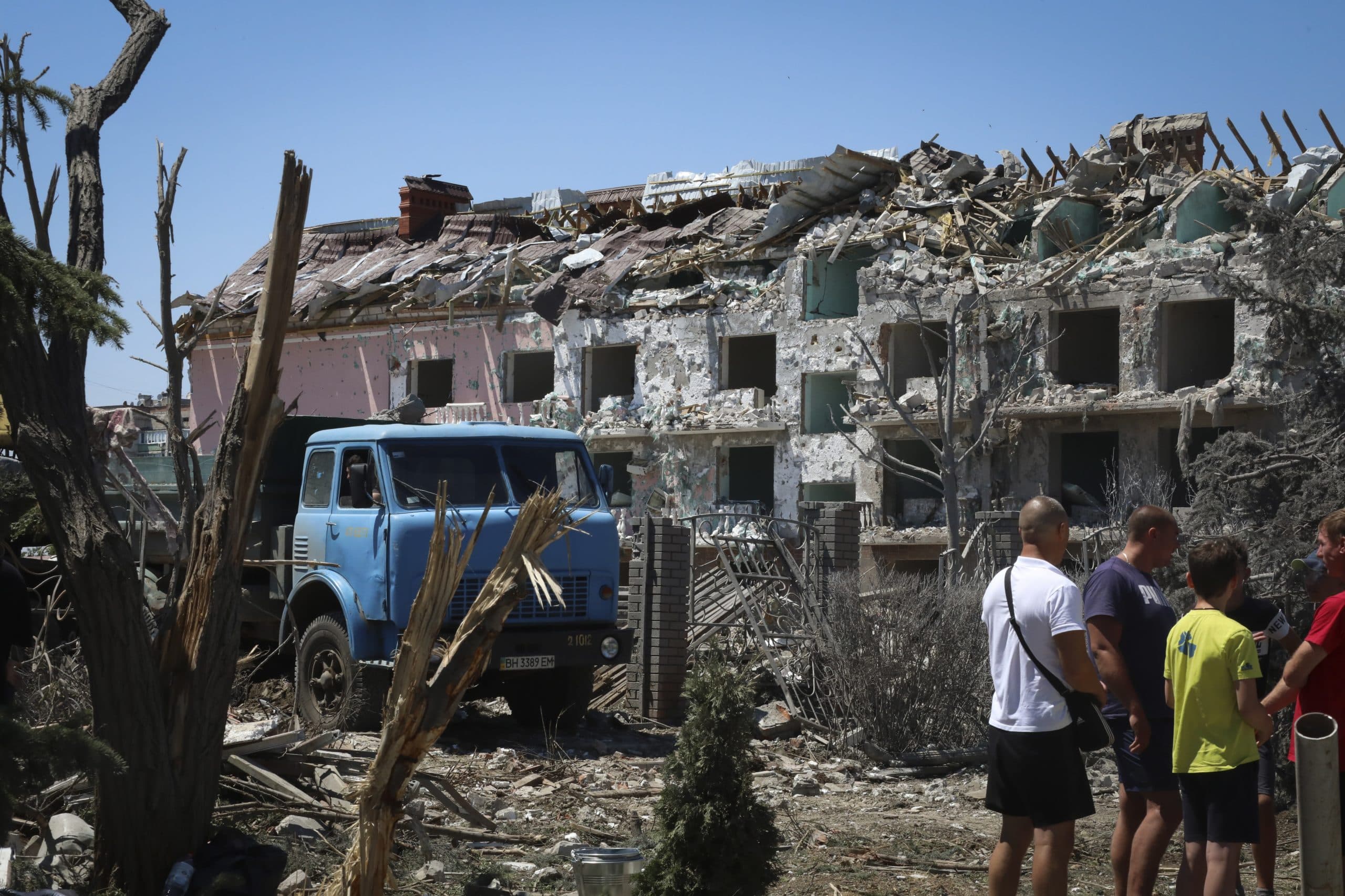 Local residents stand next to damaged residential building in the town of Serhiivka, located about 31 miles southwest of Odesa