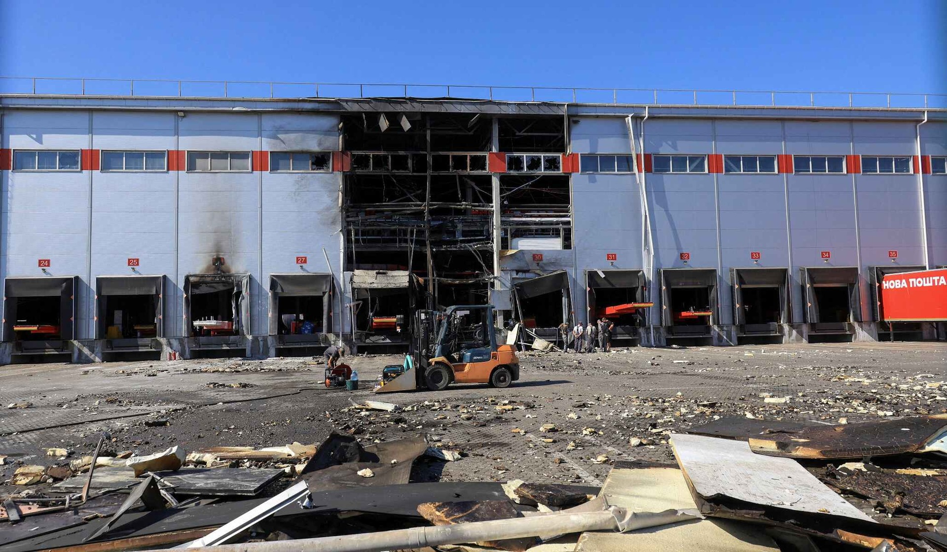 Employees remove debris outside a Nova Post sorting terminal damaged by a Russian drone strike on the outskirts of Odesa