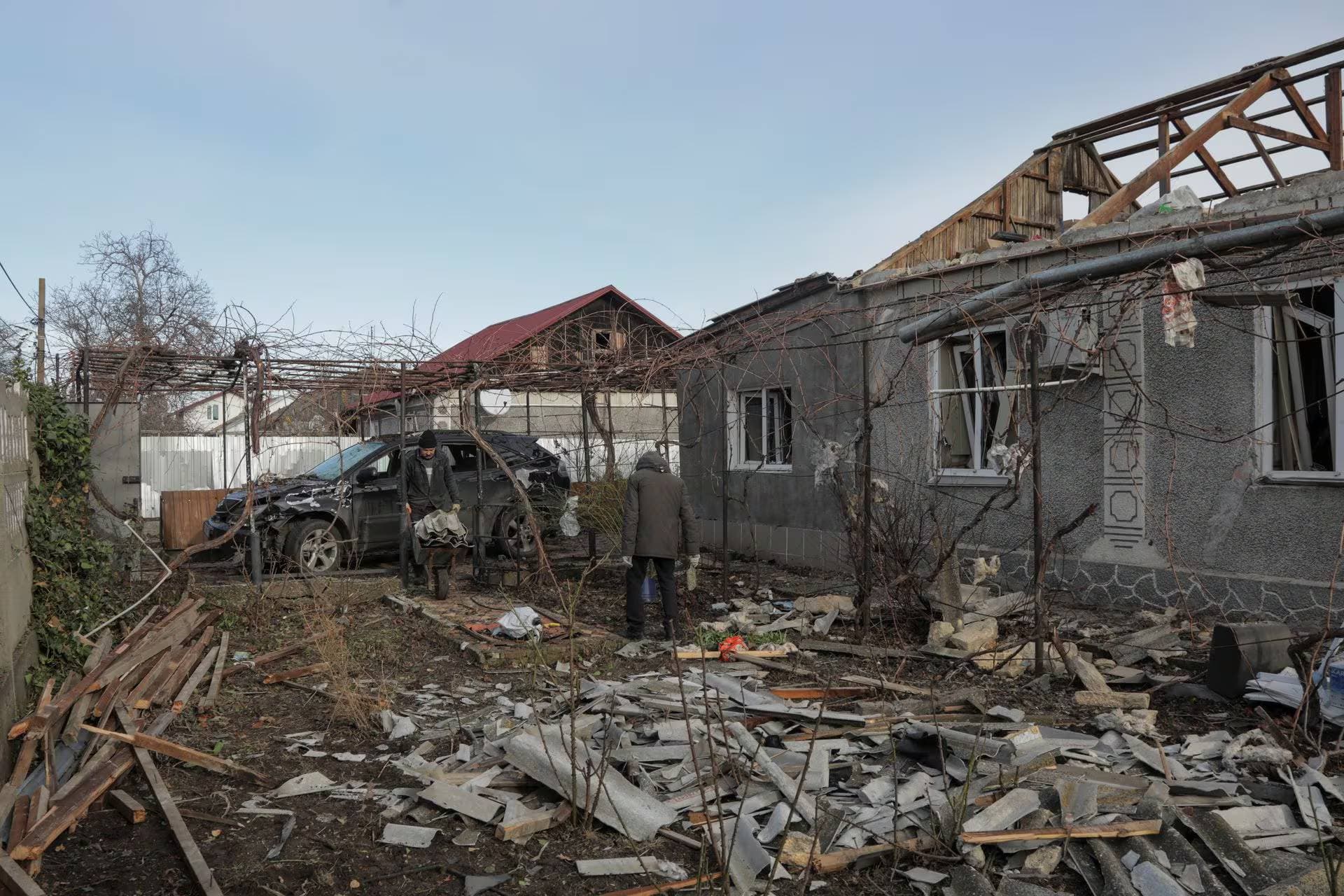 Local residents remove debris from the backyard of their house, which was damaged during a Russian drone strike in Odesa