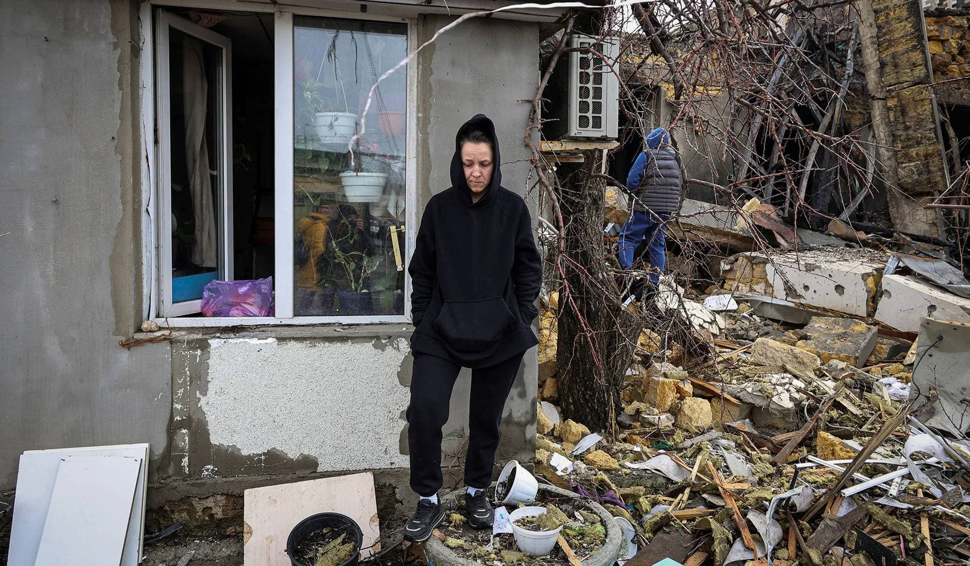 A local resident stands next to her house damaged during Russian drone and missile strikes in Odesa