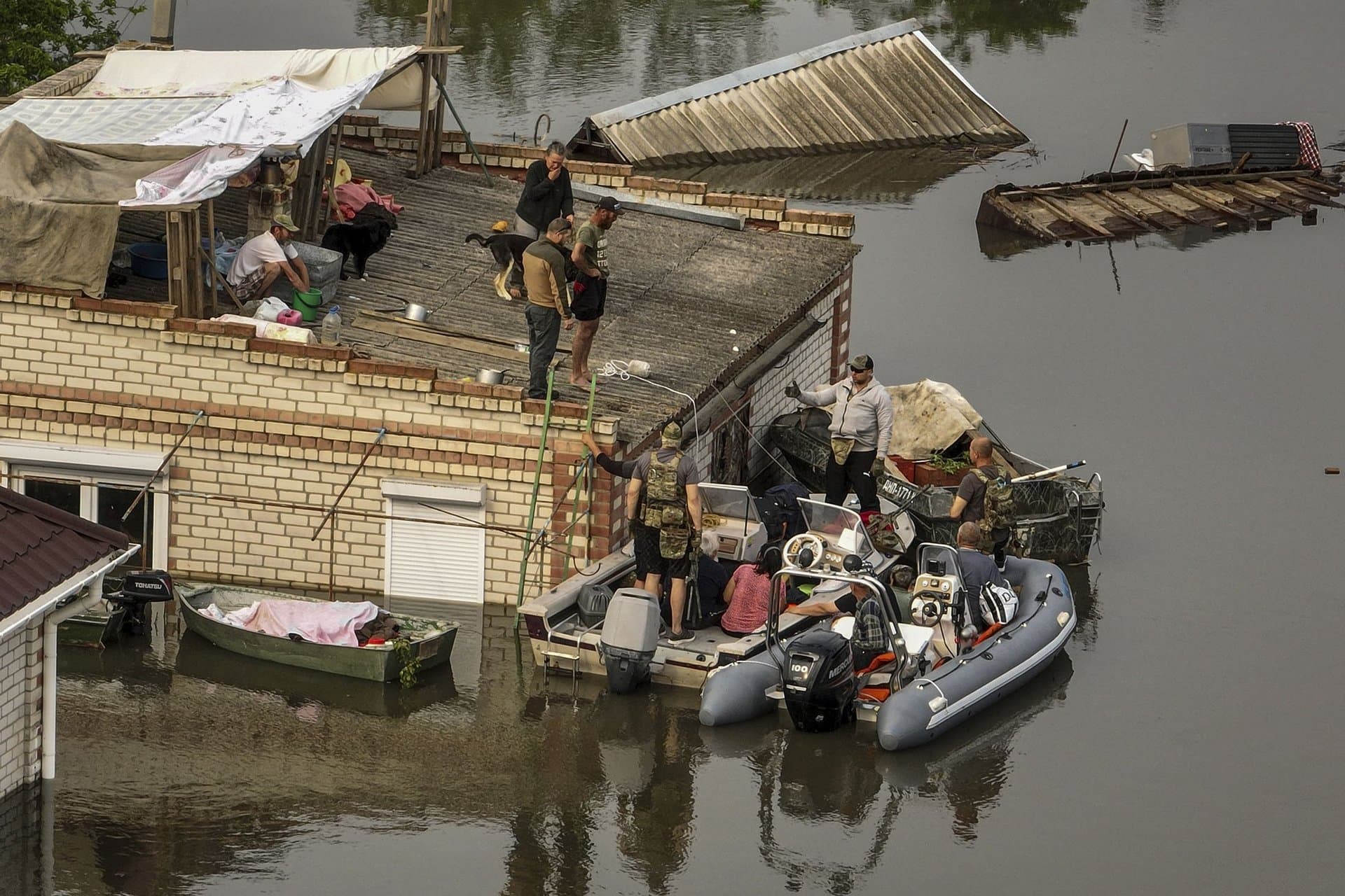 Ukrainian servicemen help residents to get down from the roof into rescue boats during an evacuation in a flooded neighborhood near Oleshky