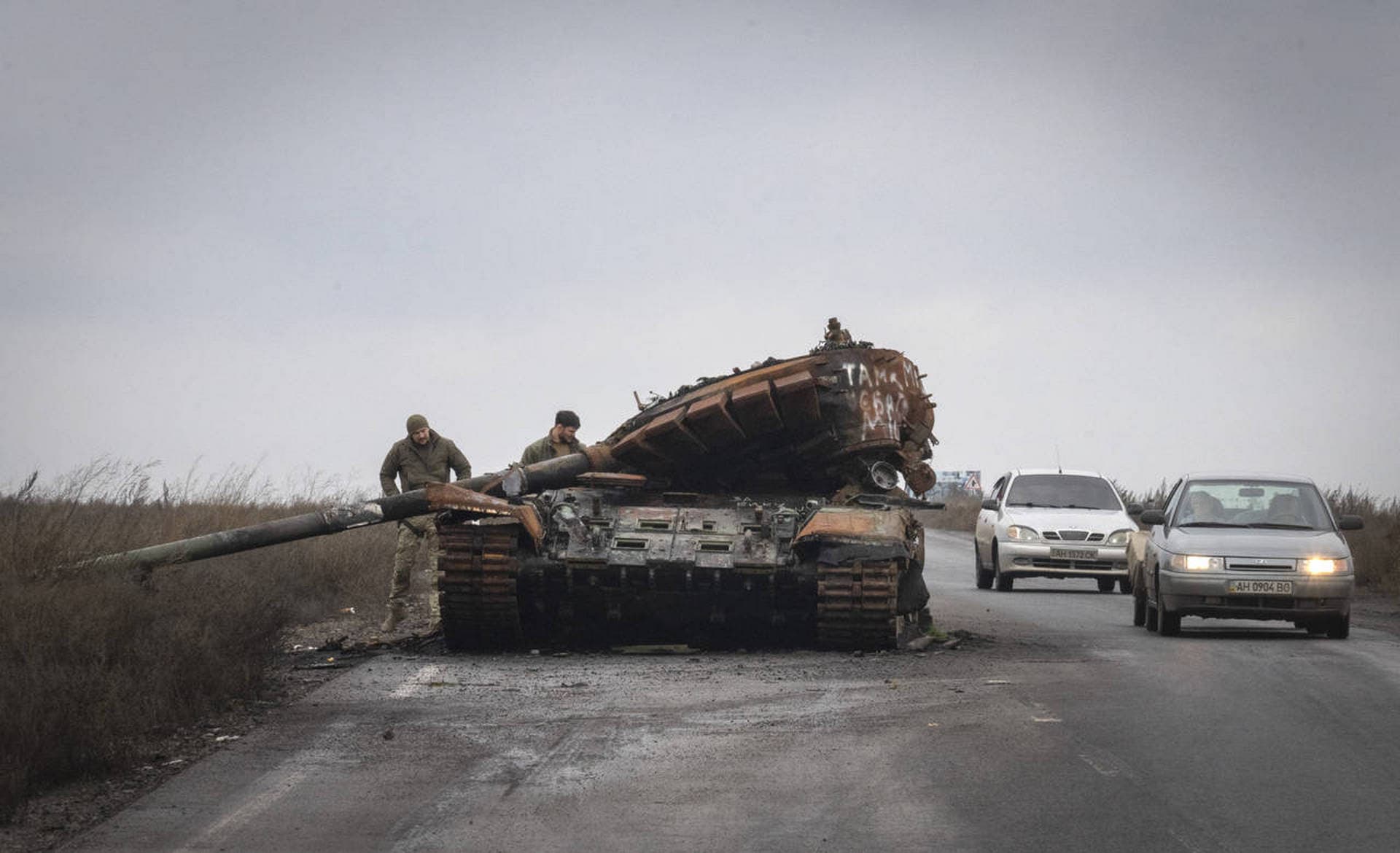 Ukrainian soldiers inspect damaged a Russian tank on a road near the recently retaken village of Kamianka