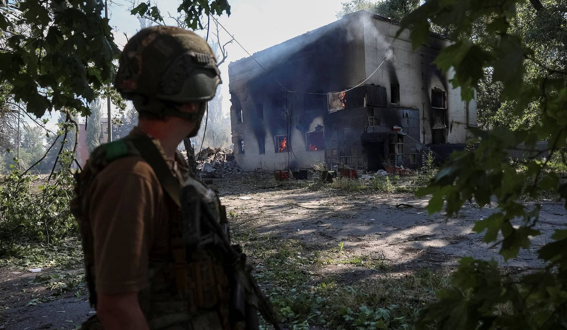 A serviceman walks near a destroyed apartment building during his combat mission in the frontline town of Dobropillia