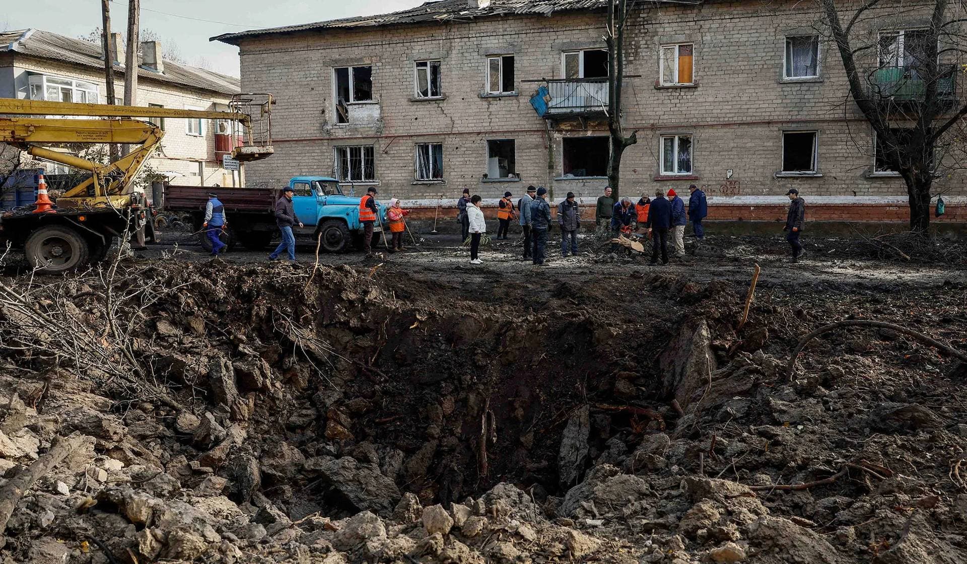 Local services workers remove debris near the crater after a Russian missile strike in Selydove