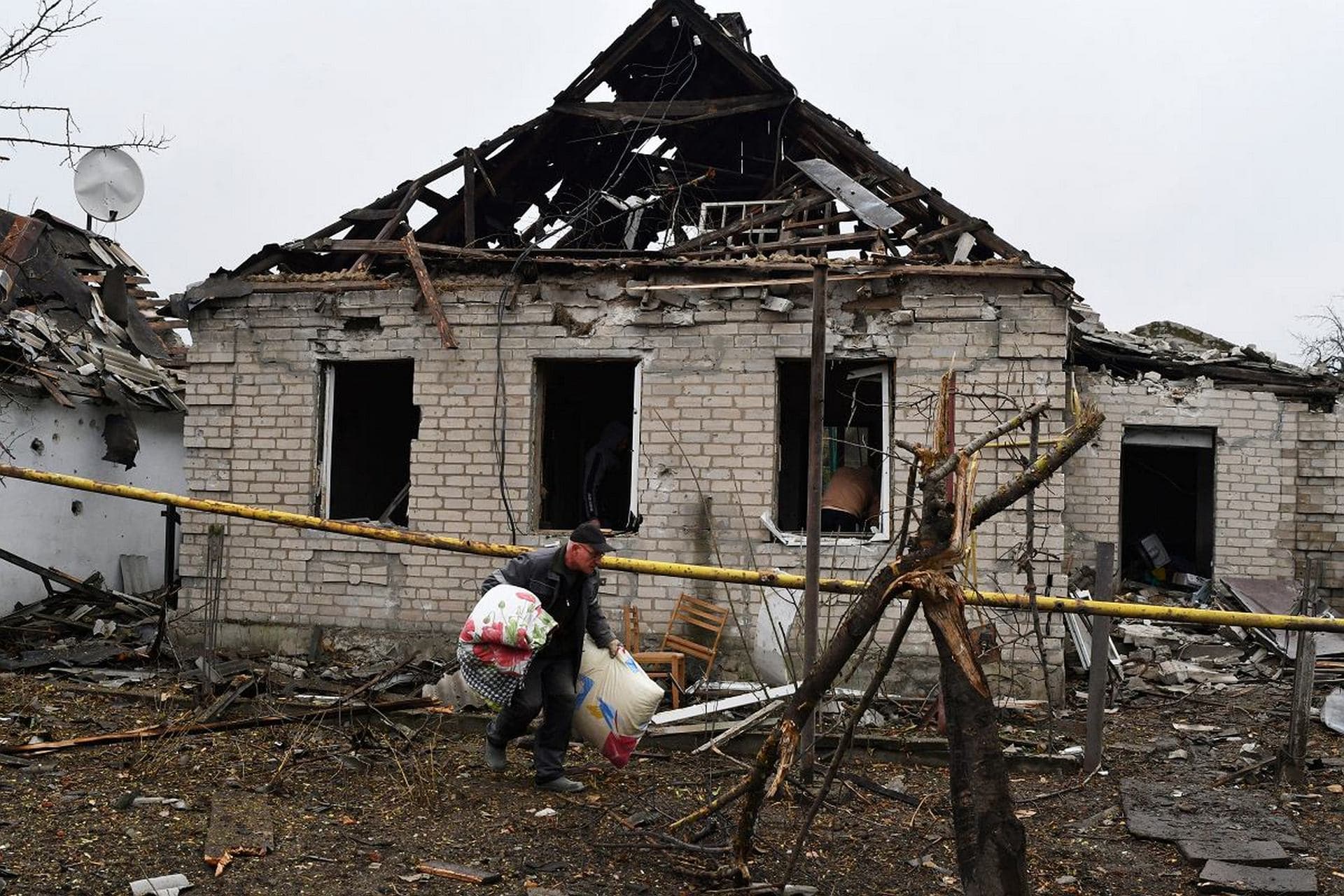 A man carries pillows from his destroyed apartment building after Russian shelling in Pokrovsk
