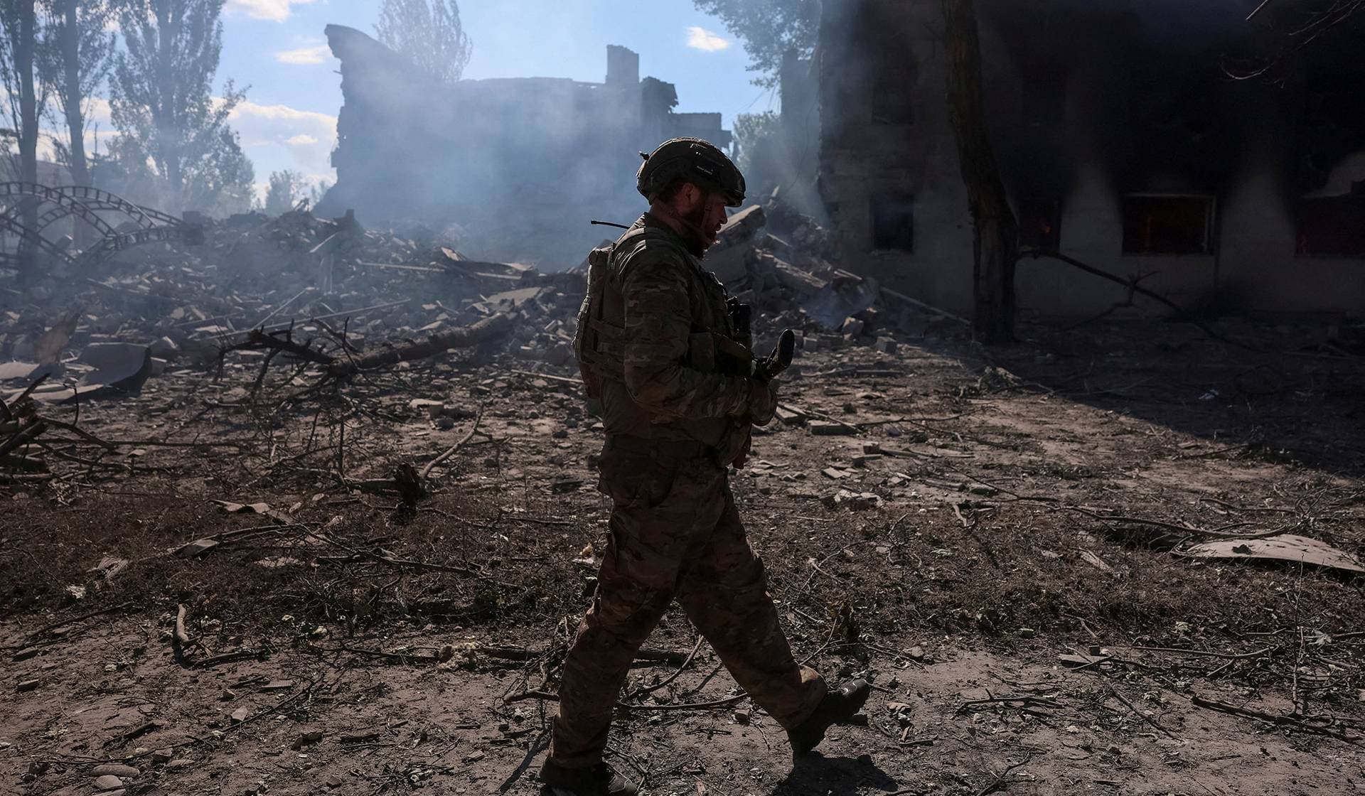 A serviceman walks near destroyed apartment buildings during his combat mission in the frontline town of Dobropillia