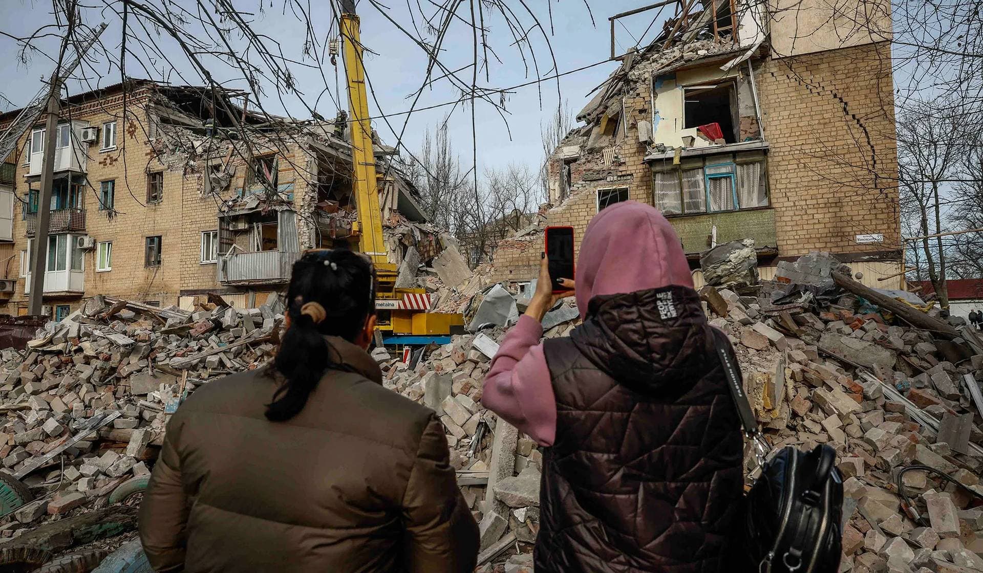 Local residents photograph the result of a Russian missile strike at the site of damaged residential house in Selydove