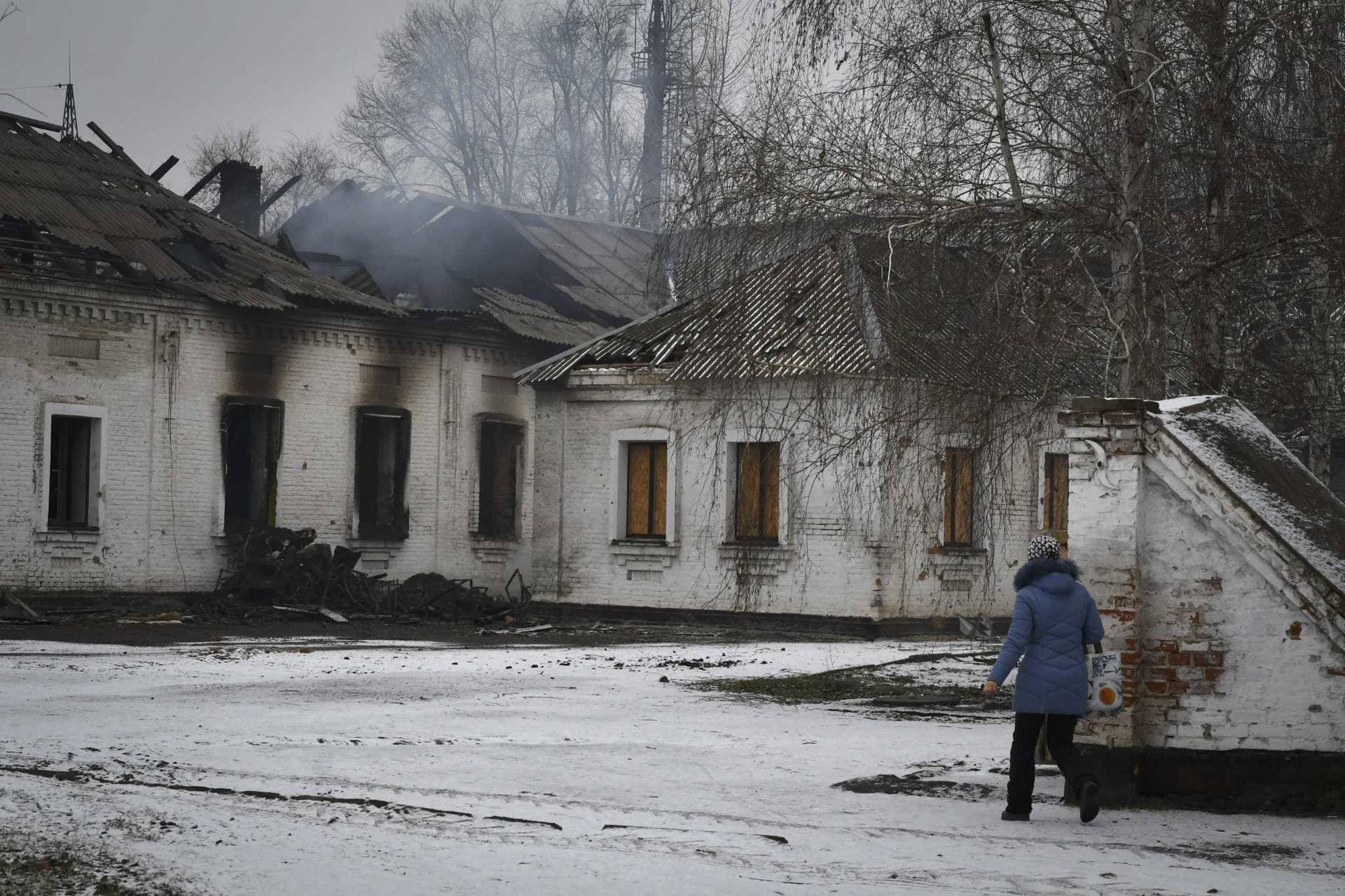 A local resident walks past a school that was damaged by Russian shelling the town of Orikhiv