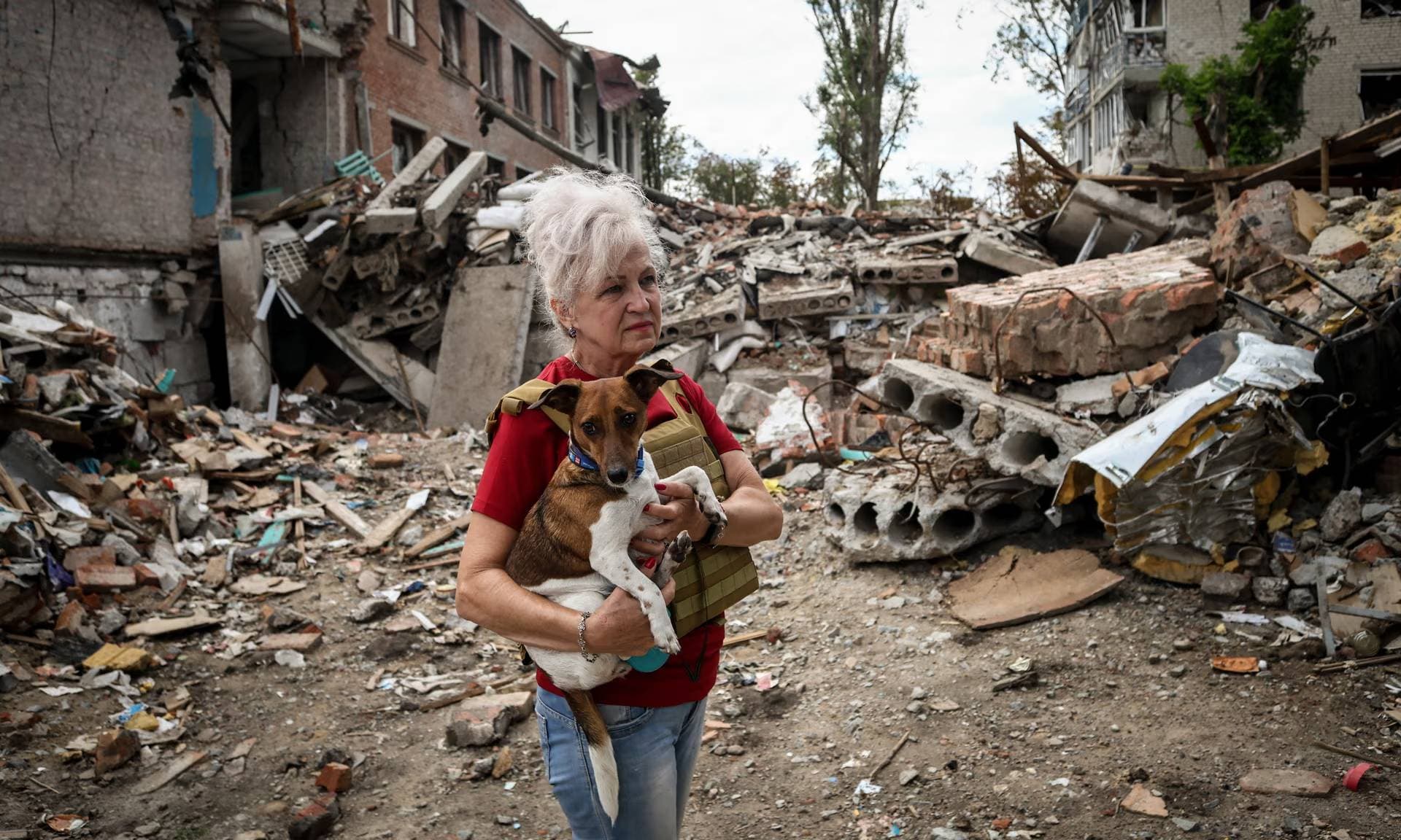 Lubov Jarova holds her dog as she walks among the rubble of a school in the frontline town of Orikhiv