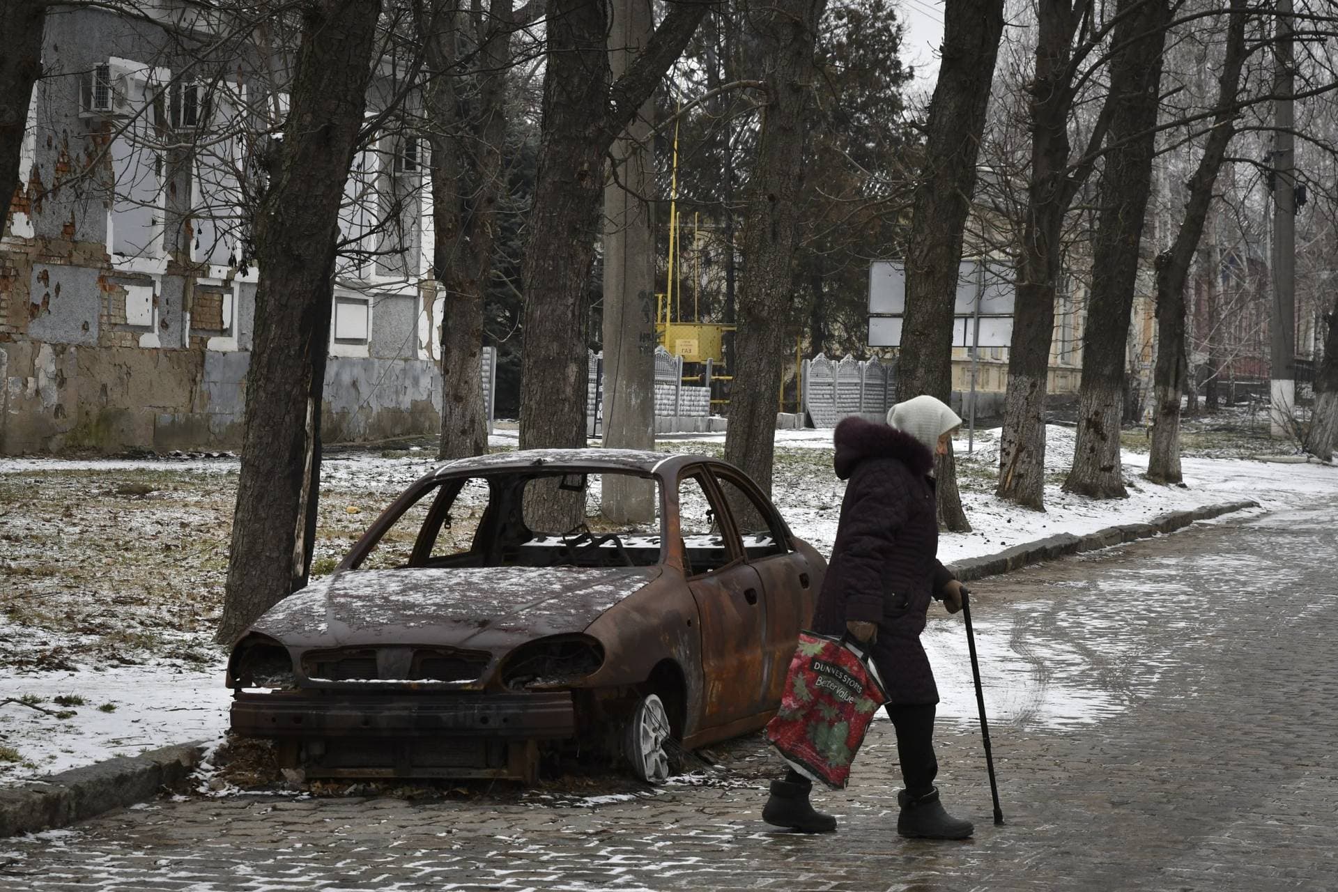 A local resident walks past a burnt car that was damaged in Russian shelling in the town of Orikhiv