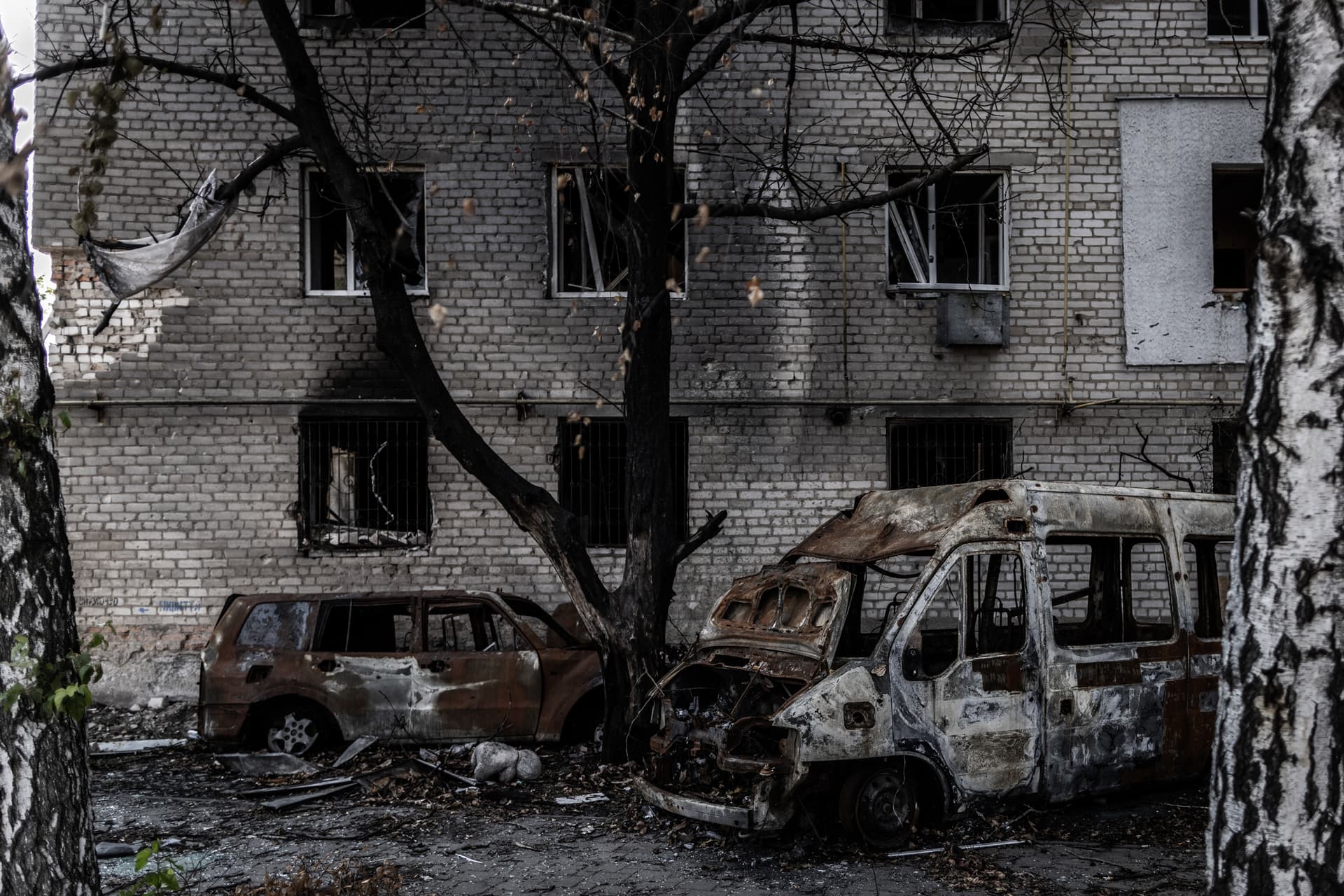 Burned cars outside a damaged apartment block in the frontline town of Orikhiv
