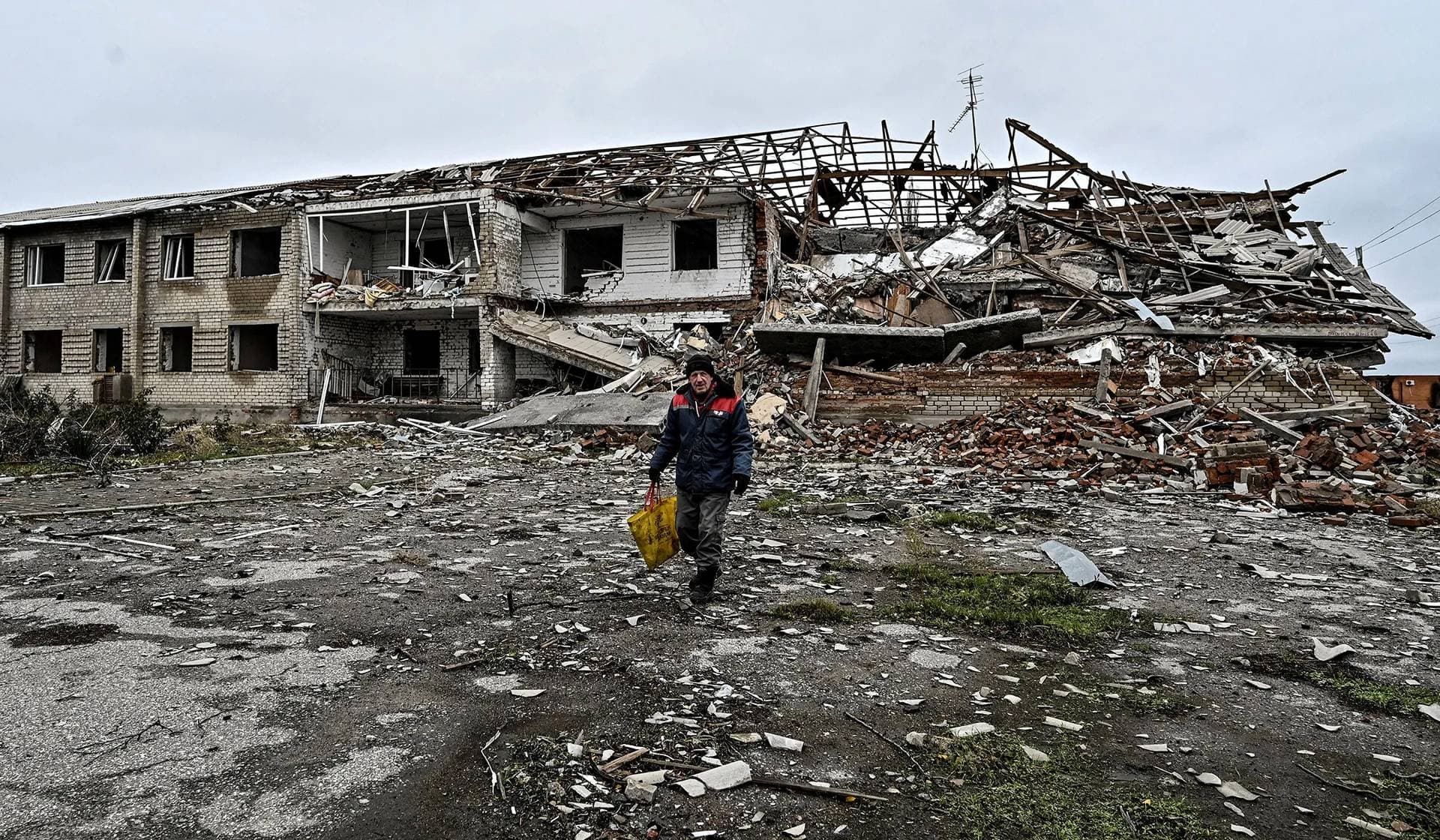 A local resident walks in front of a building heavily damaged by Russian military strikes in Orikhiv