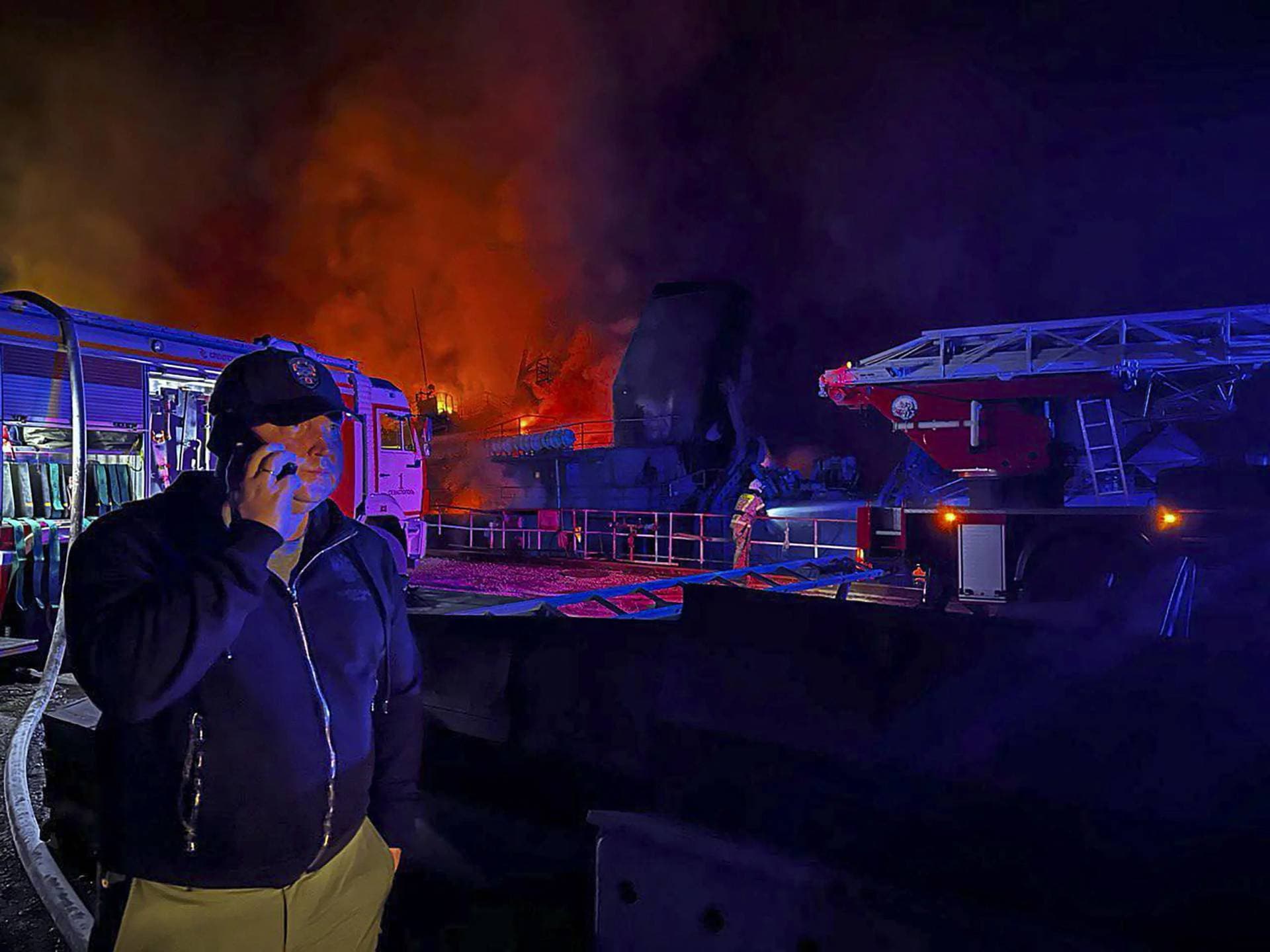 Governor of Sevastopol Mikhail Razvozhaev speaks on the mobile phone as smoke and flame rise from a burning Sevastopol shipyard