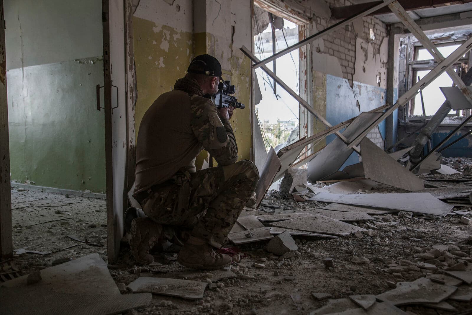 A Ukrainian soldier crouches on a position during heavy battles in the front line in Severodonetsk