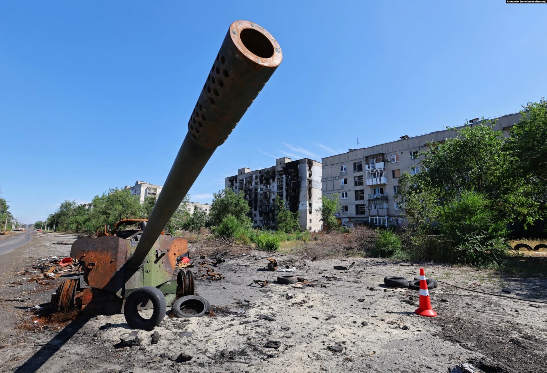 The remains of an MT-12 Rapira anti-tank gun near burned-out residential buildings
