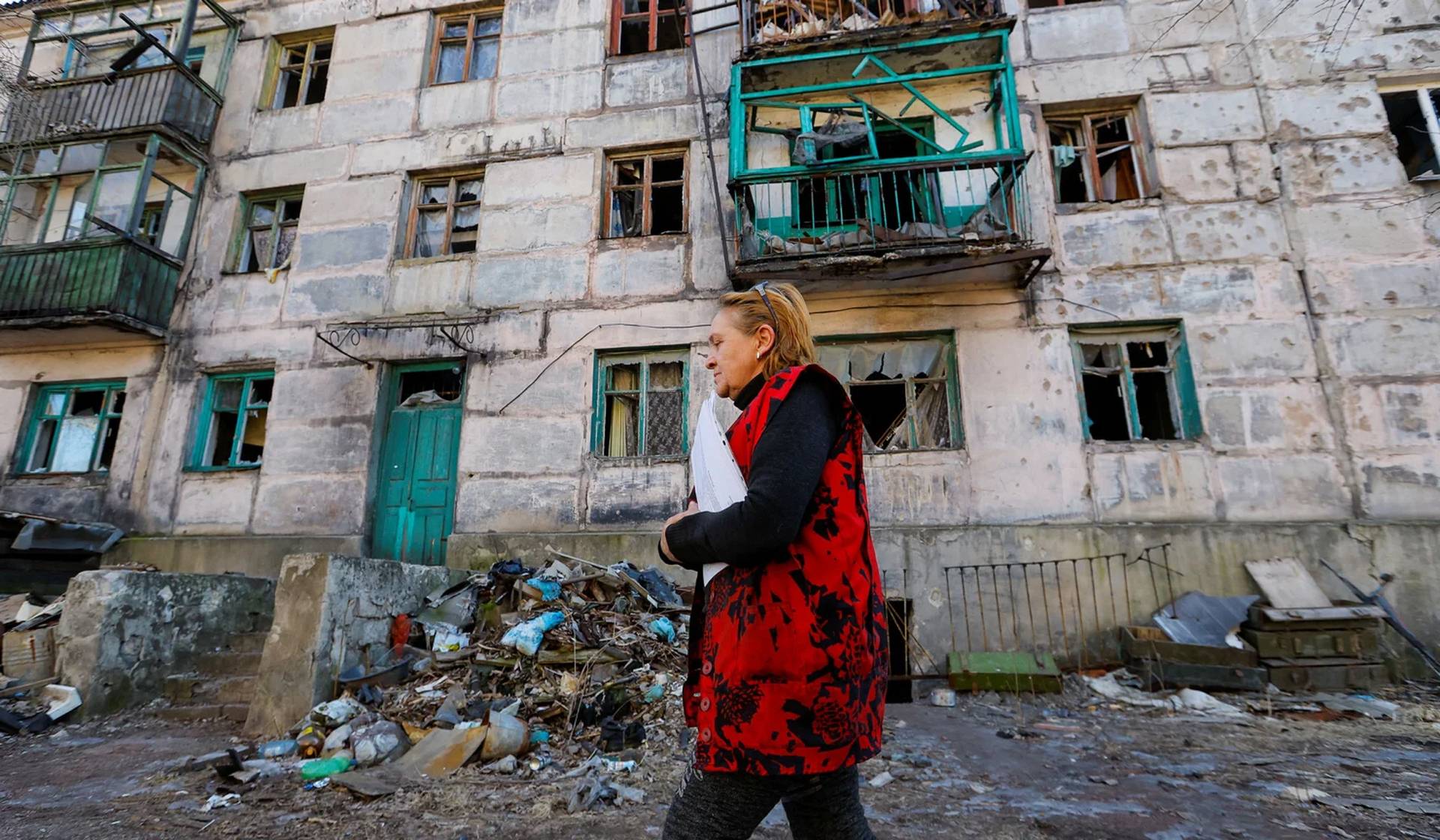 Svetlana Magur walks past a destroyed building while visiting local residents in Zolote