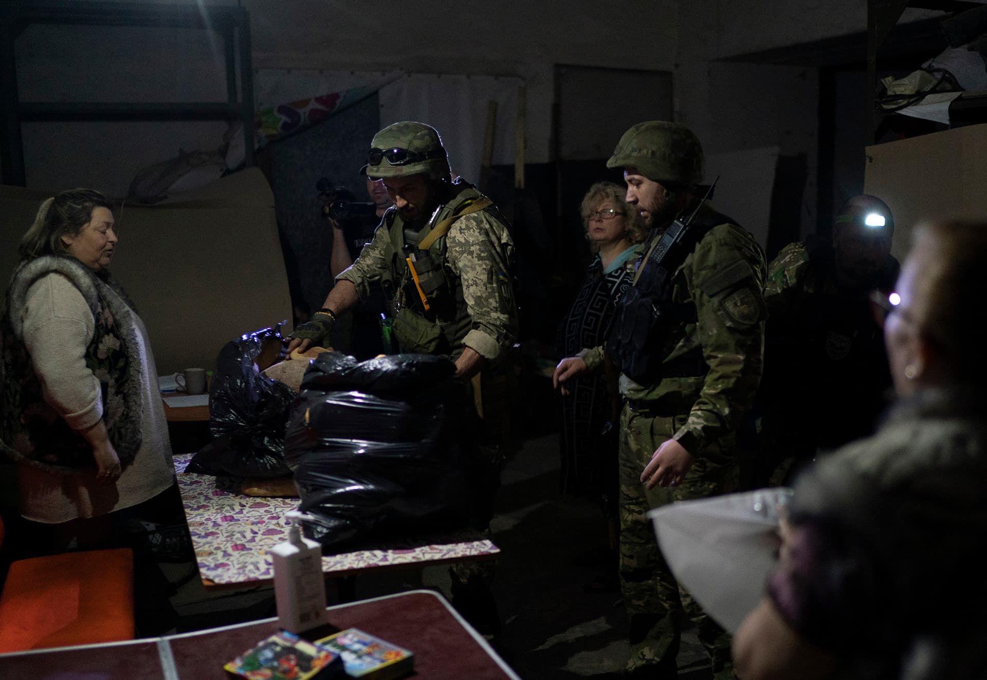 A special task force policemen deliver bags of breads donated to the people who are living inside a basement used as a bomb shelter in Severodonetsk