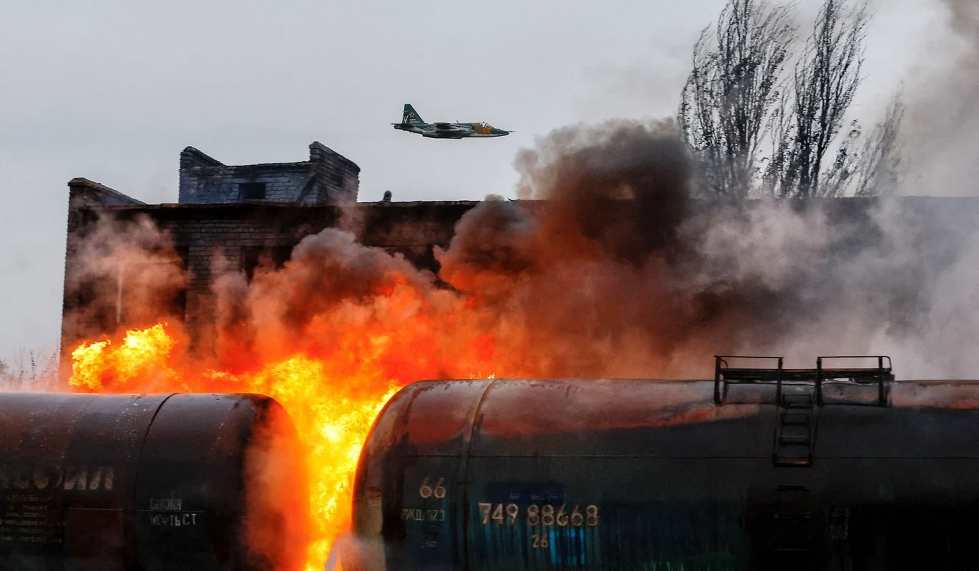 A Russian fighter jet flies above a railway junction on fire following recent shelling in Shakhtarsk
