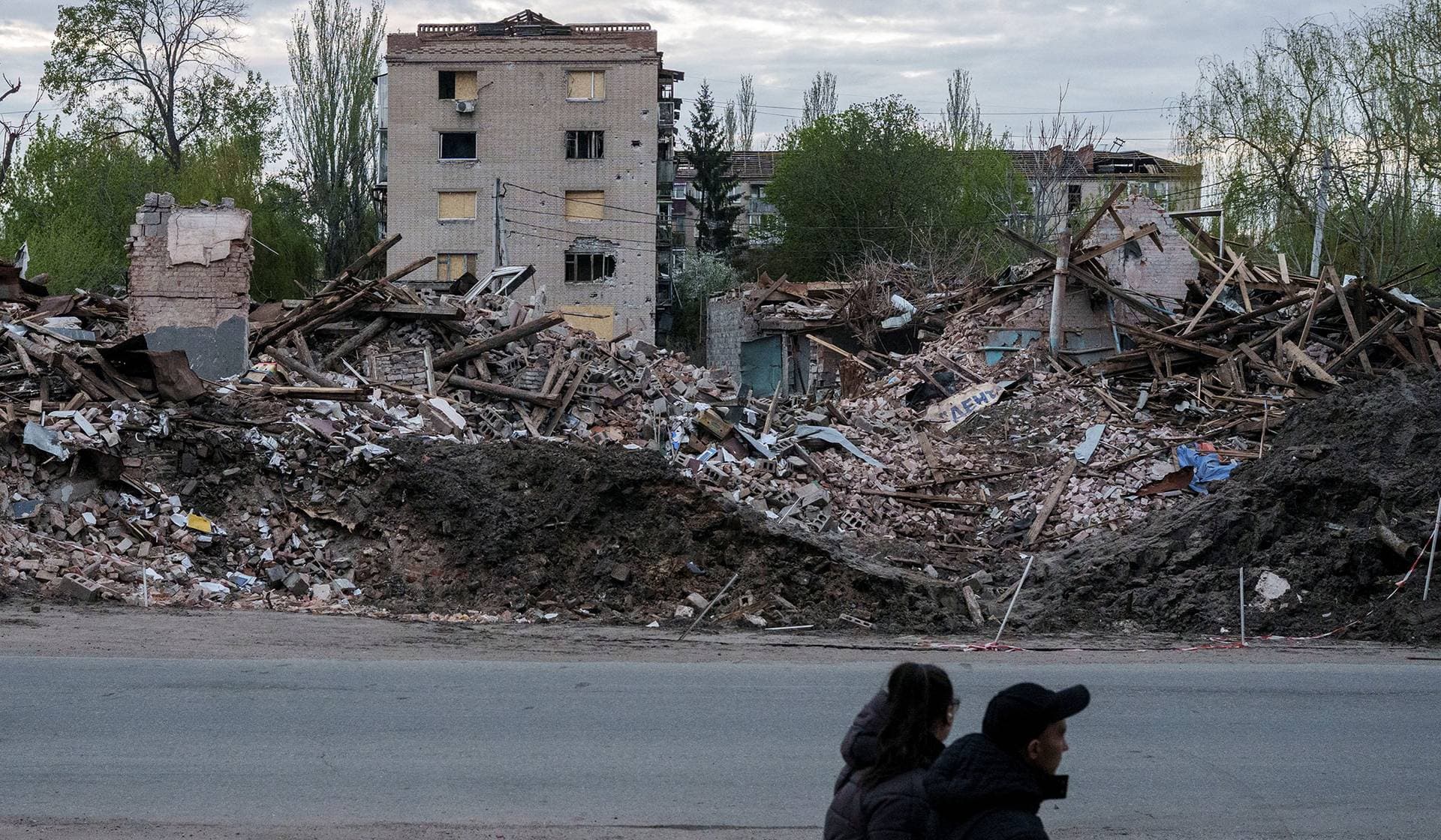 People walk next to destroyed buildings in the city of Sloviansk