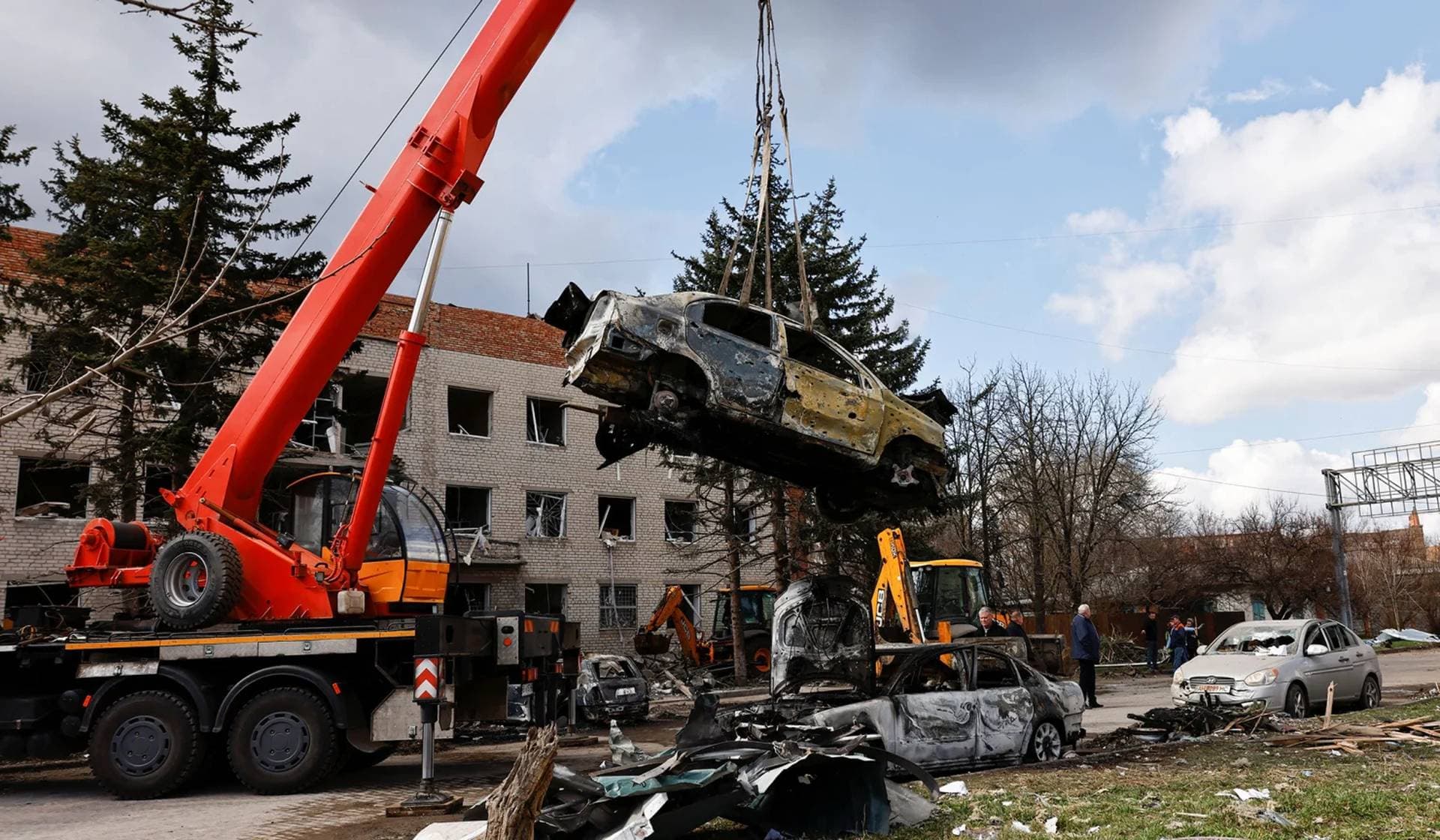 A crane lifts a damaged vehicle in the aftermath of deadly shelling of an army office building in Sloviansk