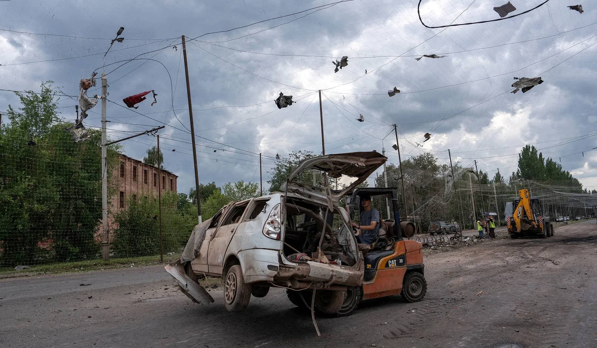 Communal workers clean a road at a site of a Russian air strike in the frontline city of Sloviansk