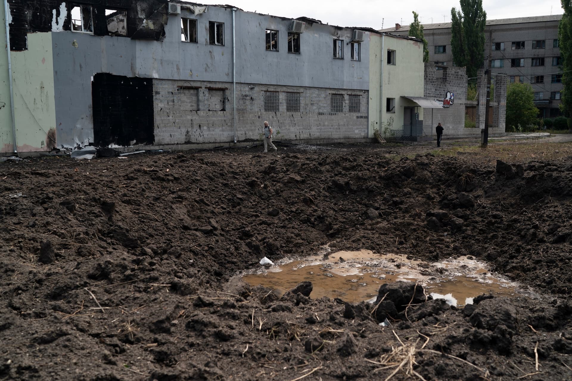 People walk past a crater from an explosion that hit an area near the Ukrainian Red Cross Society during a Russian attack yesterday in Sloviansk