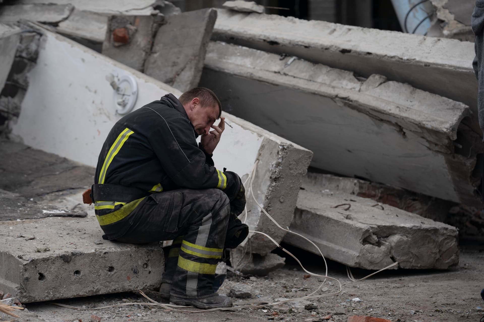 A rescue worker takes a pause as he sits on the debris at the scene where a woman was found dead after a Russian attack that heavily damaged a school in Mykolaivka
