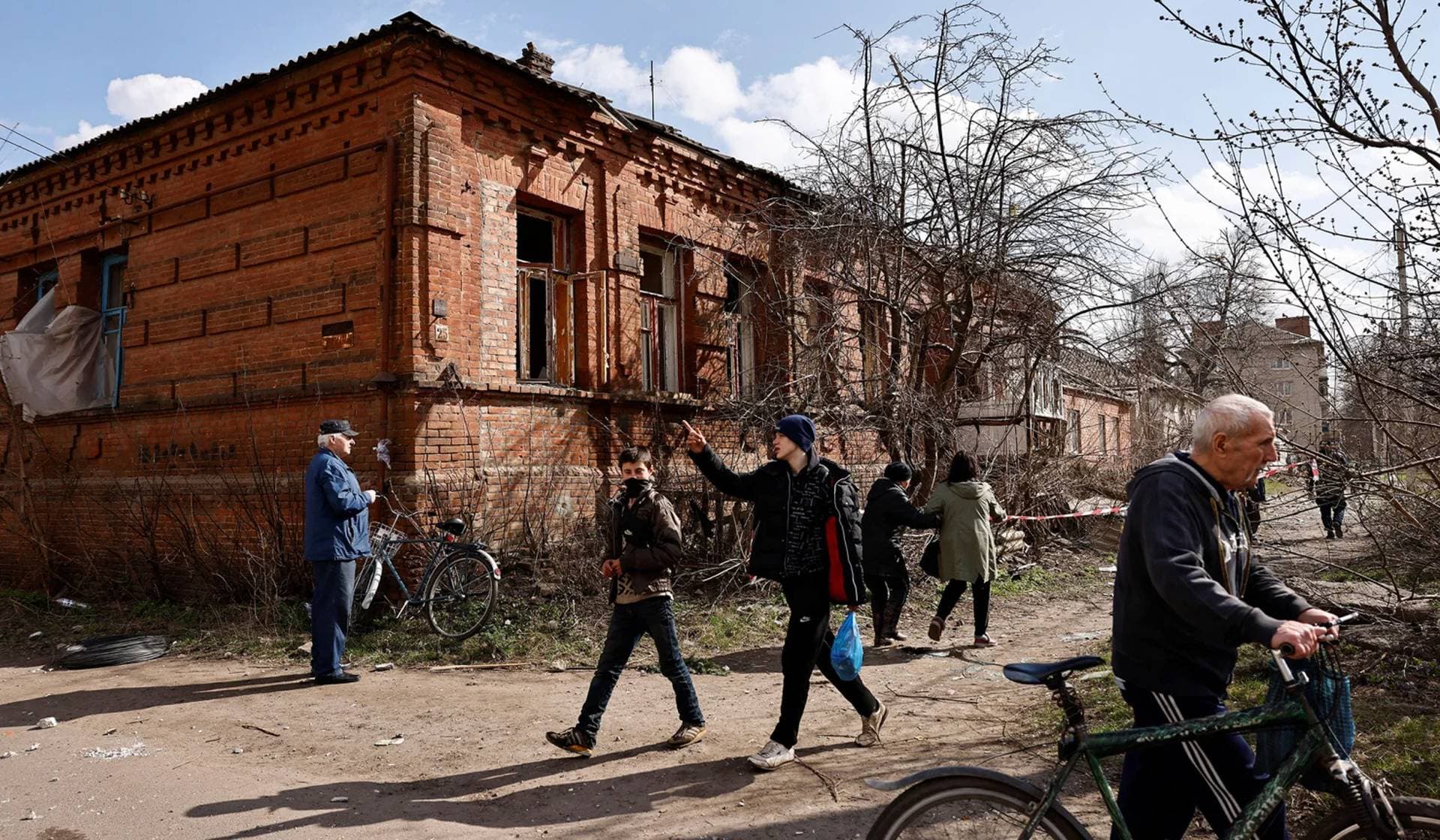 People walk in the aftermath of deadly shelling of an army office building in Sloviansk