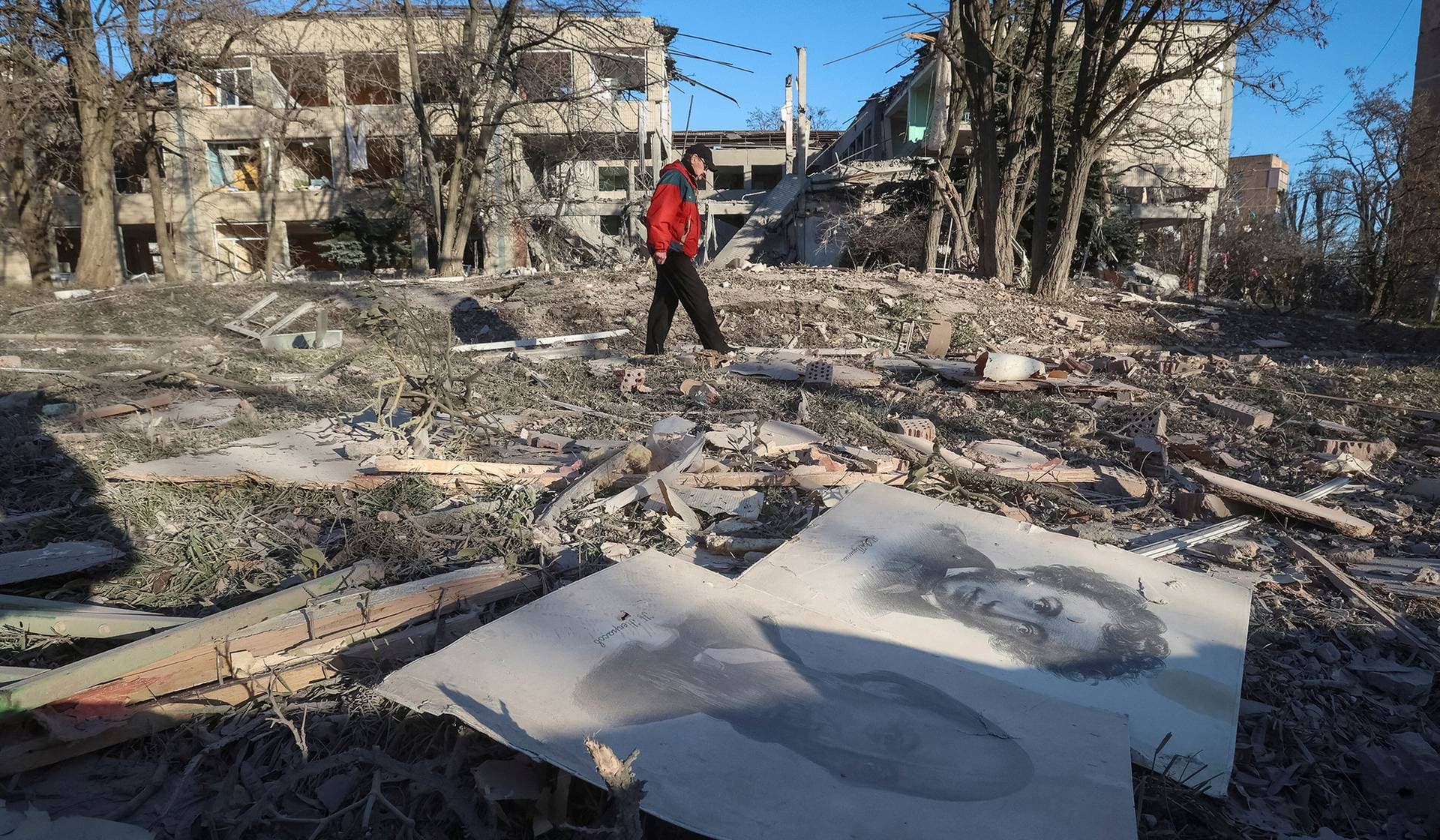 A resident walks near a school building destroyed during Russian air strikes in the town of Sloviansk
