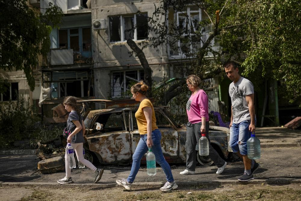 Residents carry water in front of an apartment building damaged in an overnight missile strike, in Sloviansk