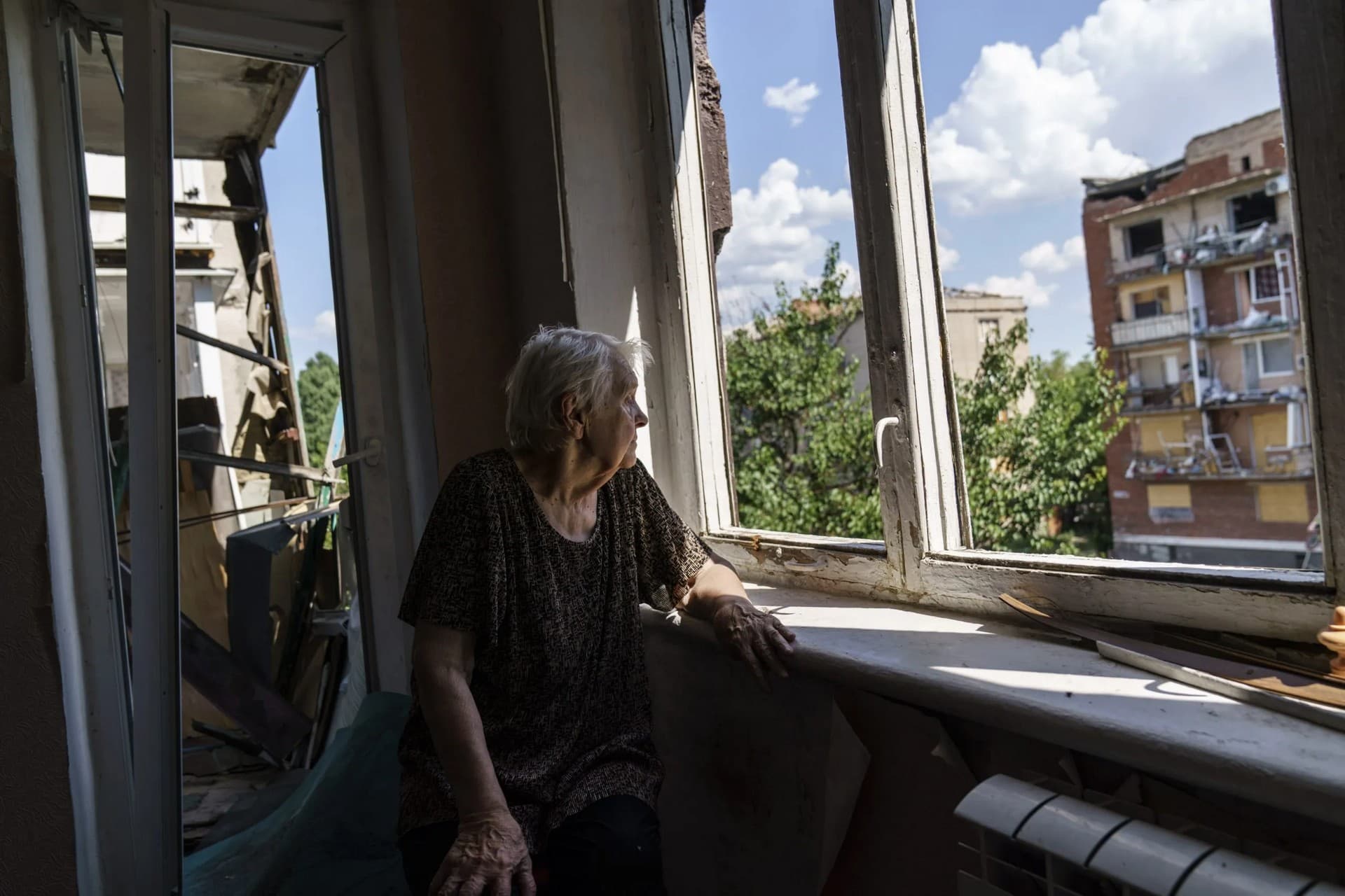 Ida Svystunova, 89, looks out the damaged room adjoining her apartment from a May rocket attack in Sloviansk