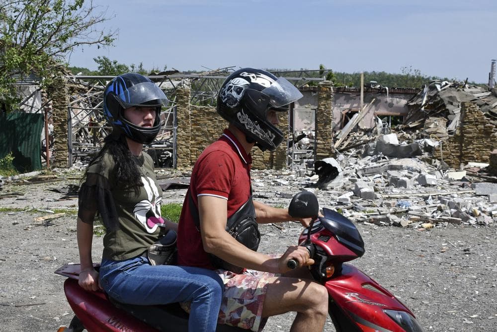 People ride a bike past a building damaged by an overnight missile strike in Sloviansk
