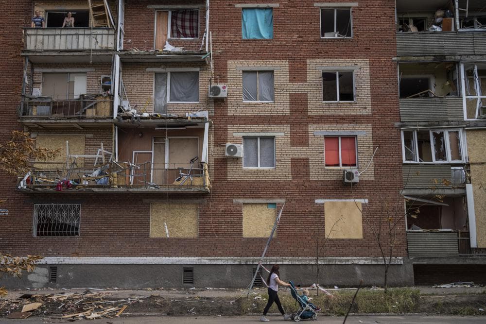 A woman pushes a baby stroller near a building damaged during a Russian attack in Slovyansk