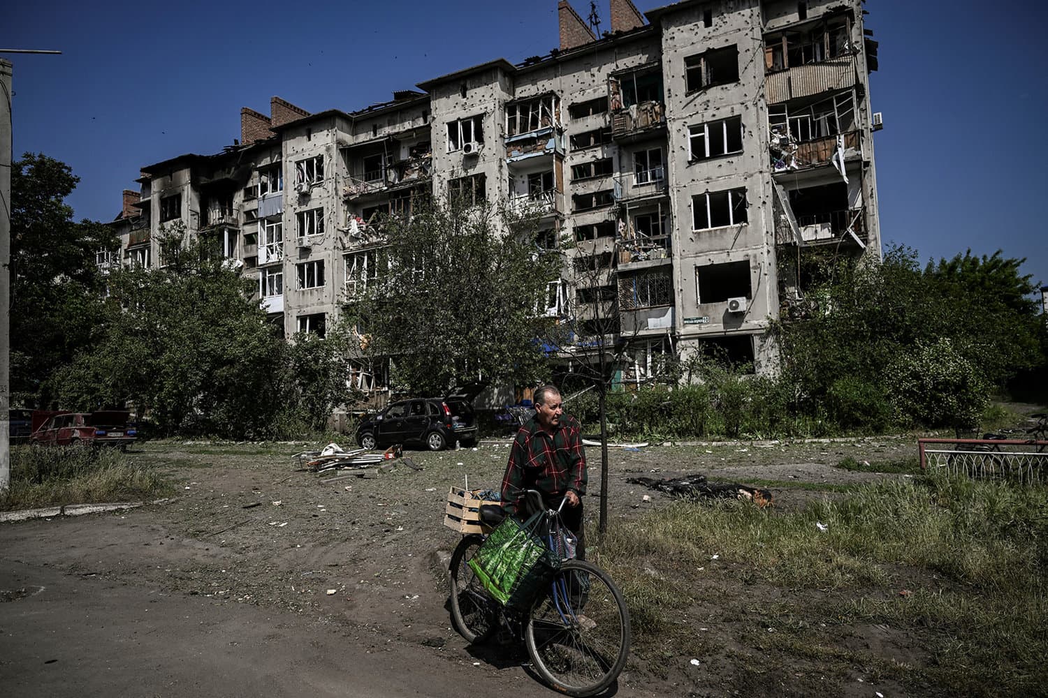 An eldery man walks by a damaged appartment building after a strike in the city of Slovyansk